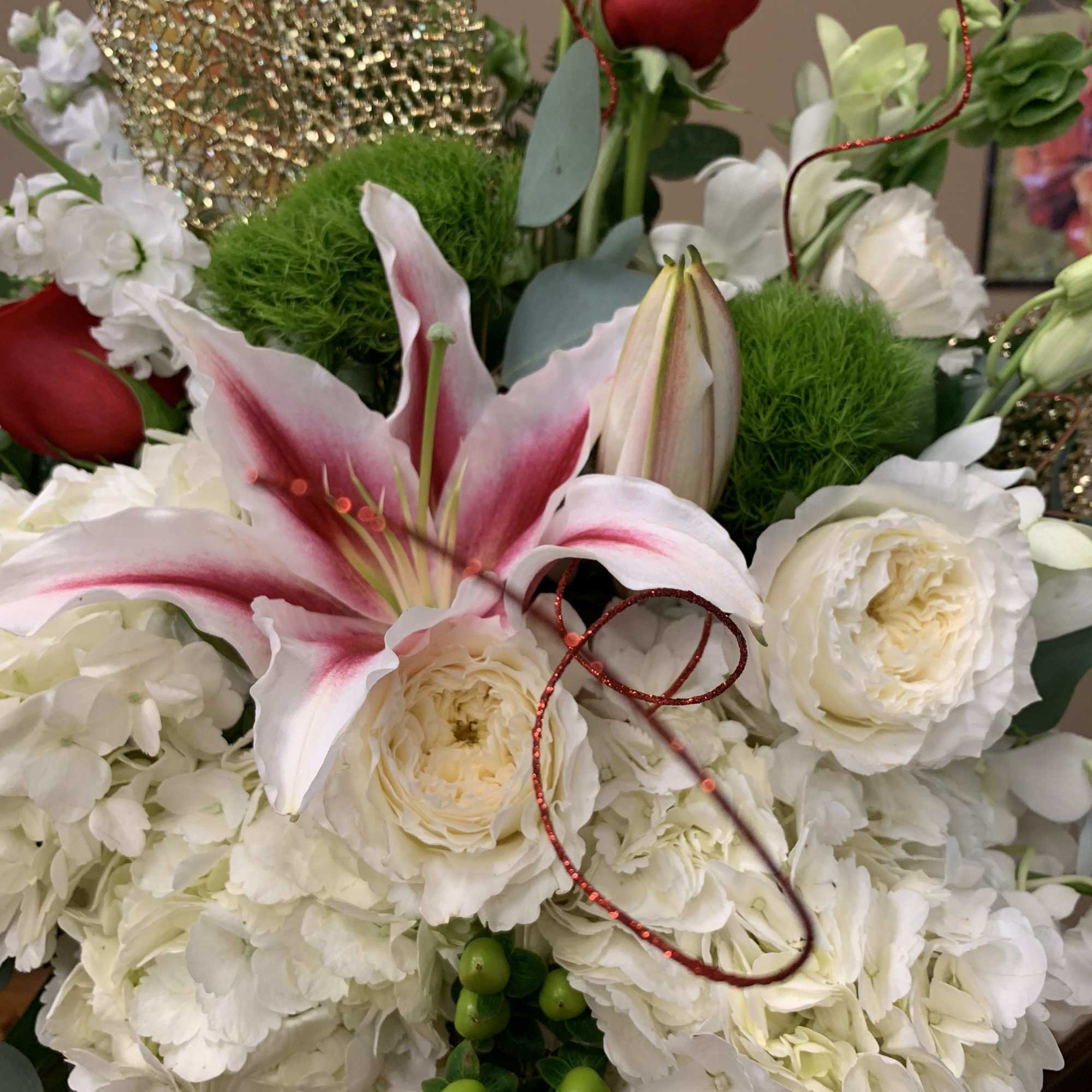 White floral arrangement with pink lilies and red ornaments
