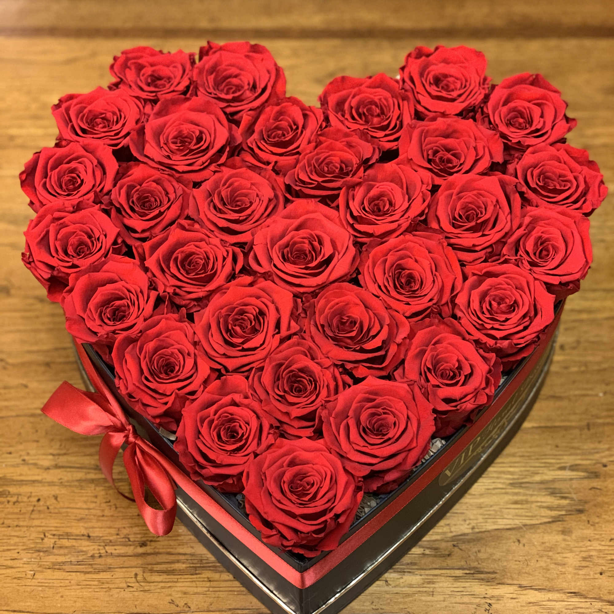 Heart-shaped box filled with red roses and tied with a red ribbon
