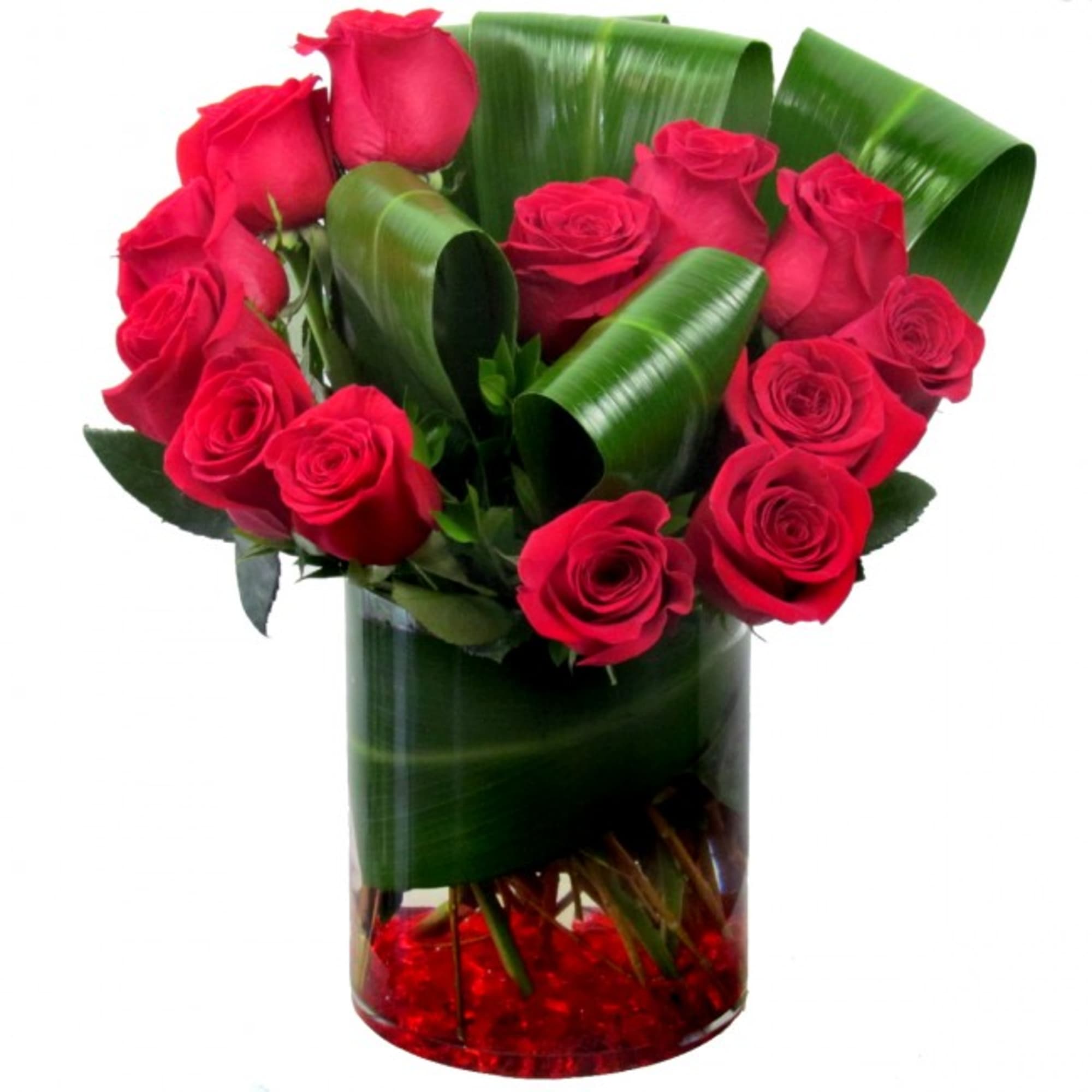 Red roses arranged in a clear glass vase with curled green leaves
