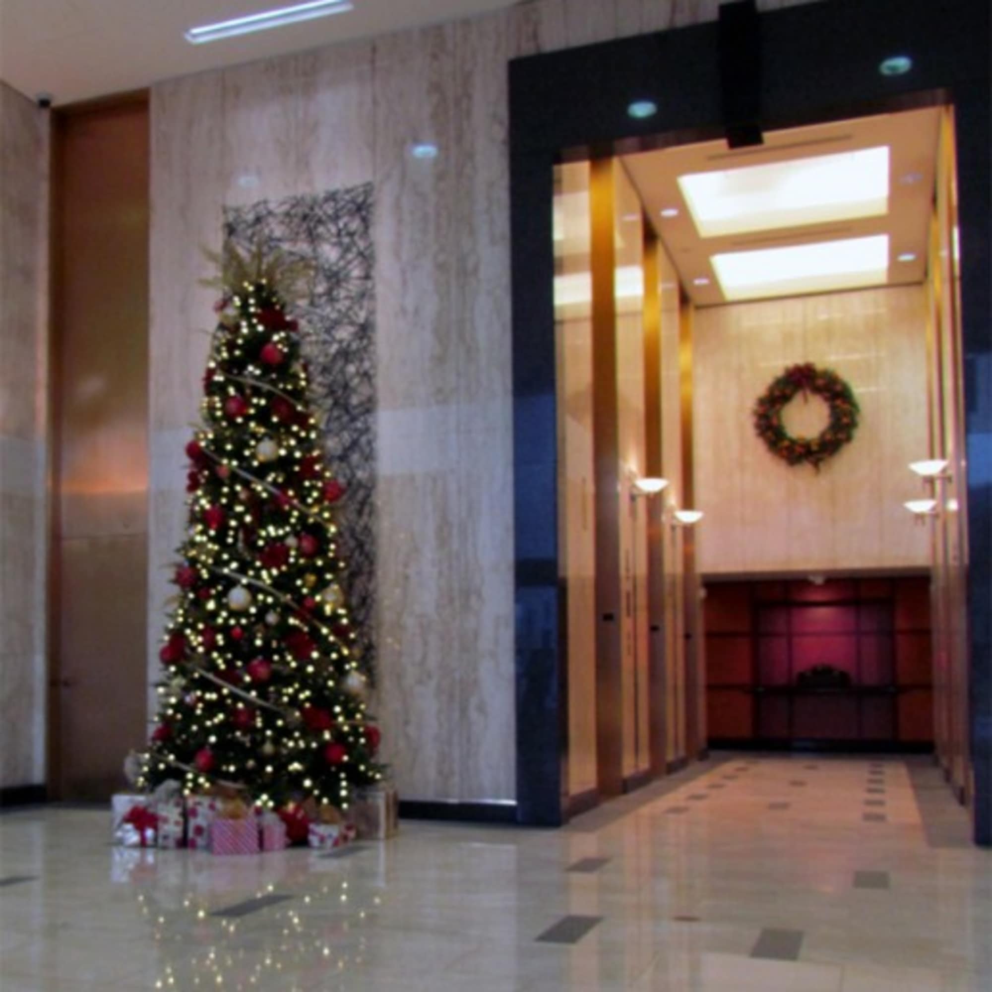 Decorated Christmas tree with lights and wrapped gifts in a lobby