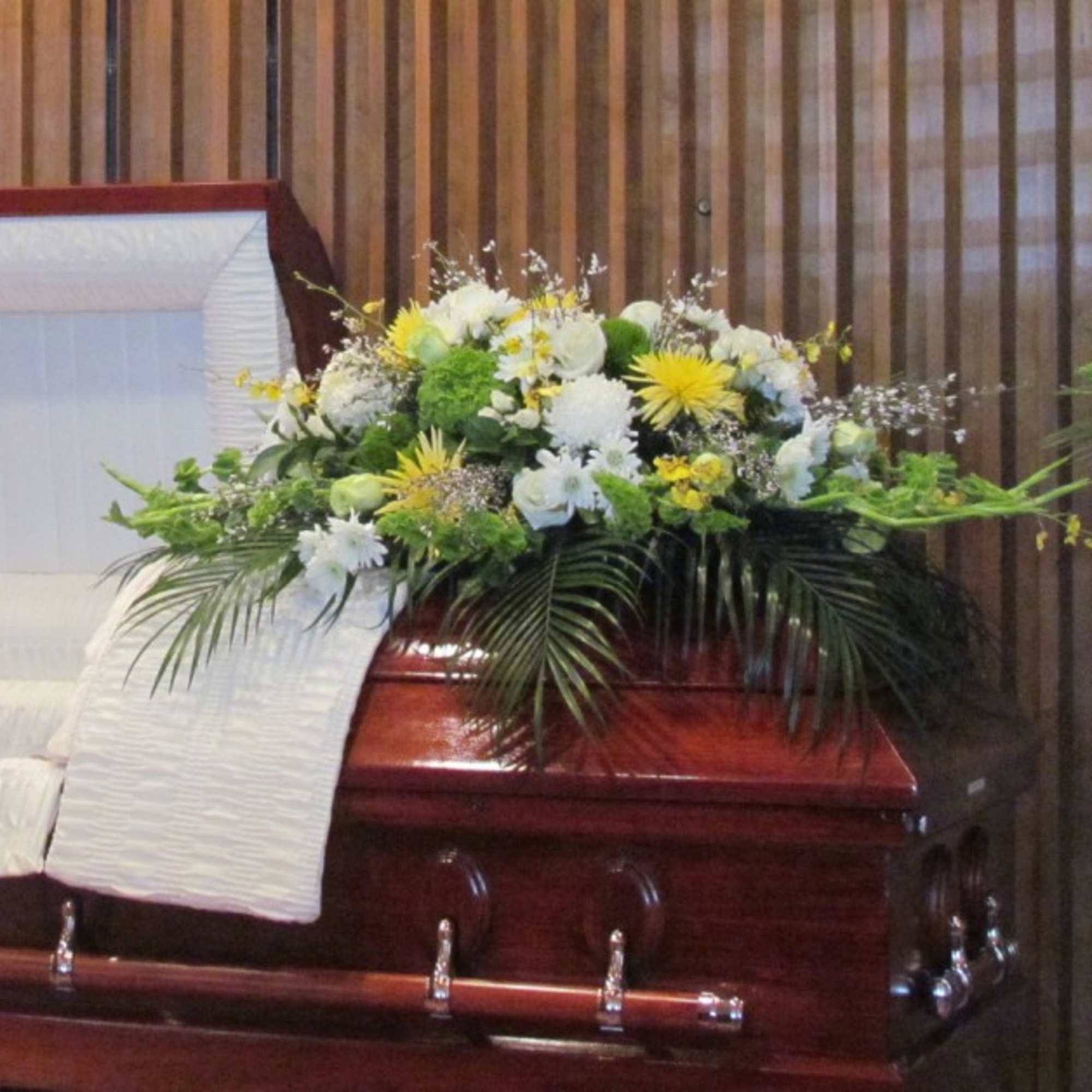White and yellow floral spray on a casket
