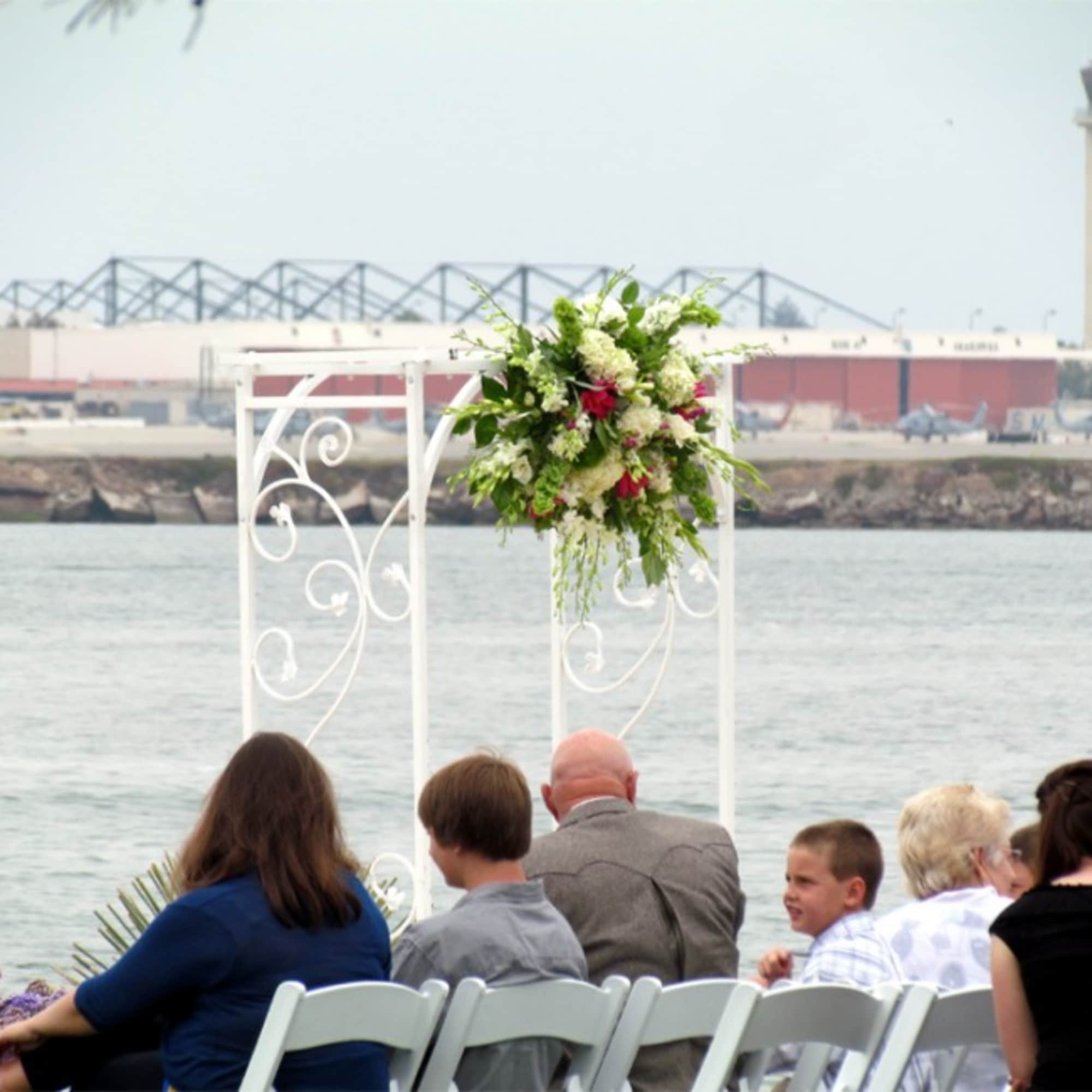 Floral arrangement on a white wedding arch by the water