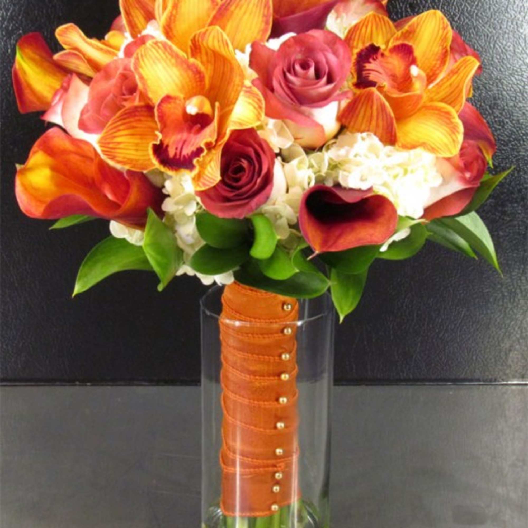 Orange orchids and red roses in a clear glass vase