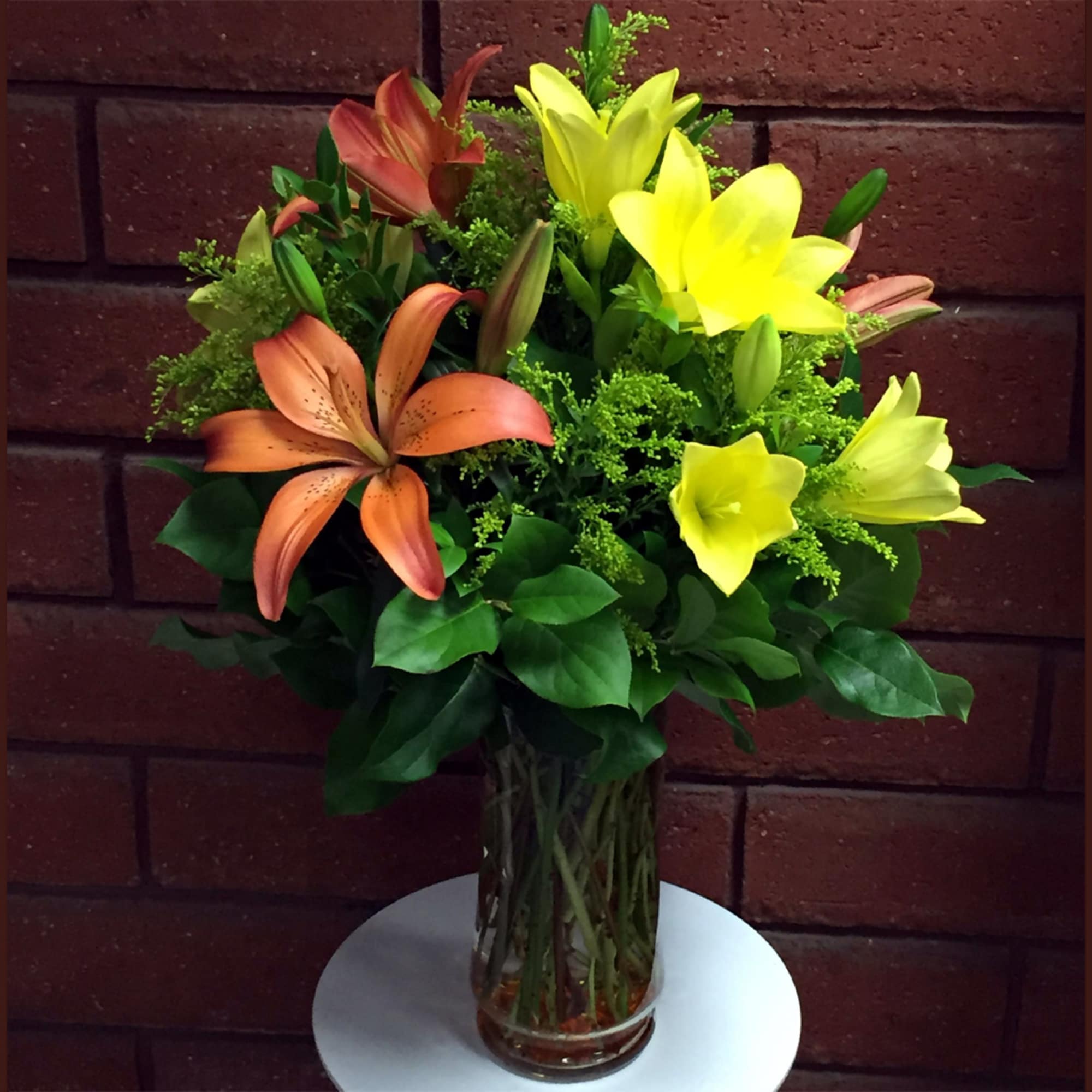 Bouquet of orange and yellow lilies in a clear glass vase