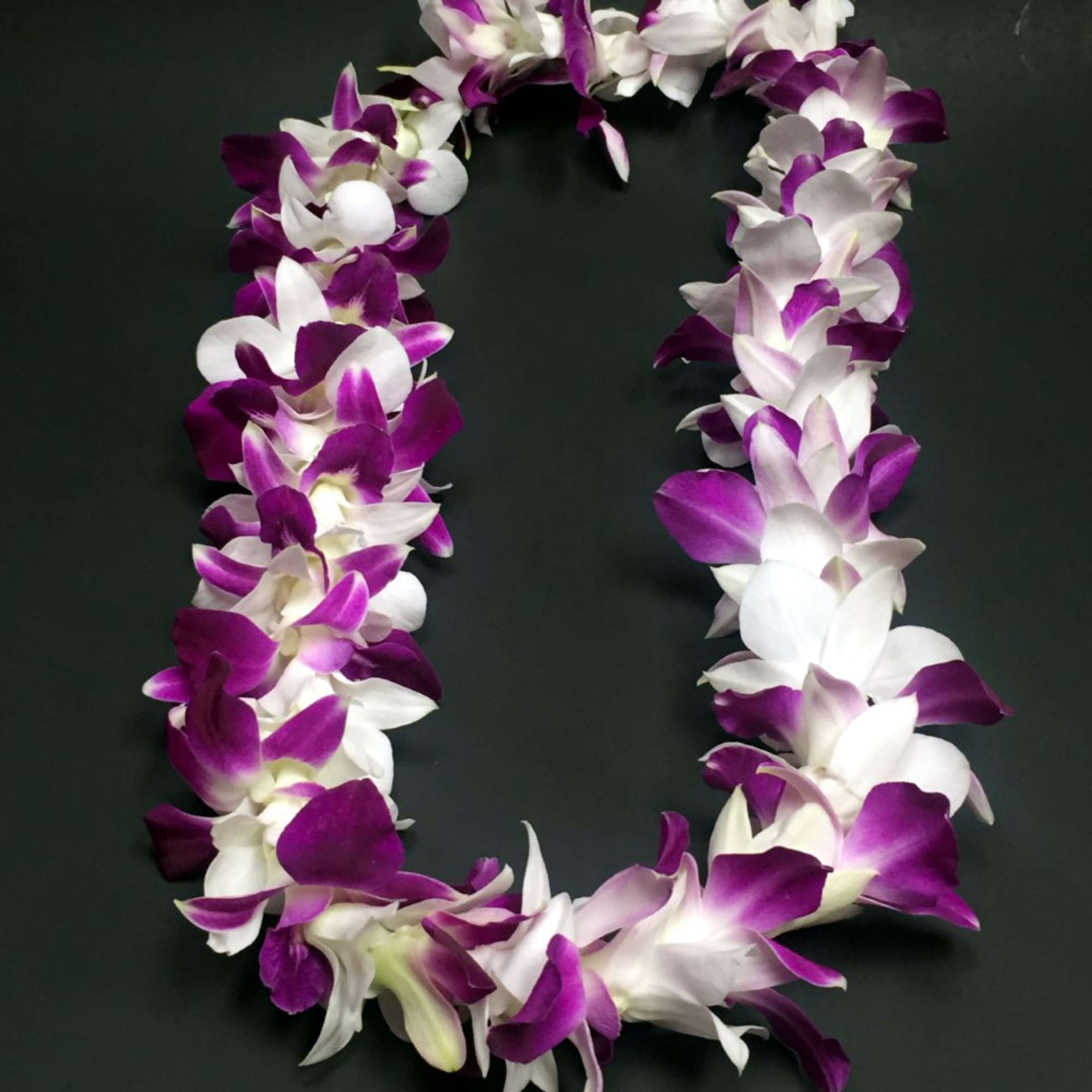 Purple and white orchid lei on a dark background, photo 2 of 3