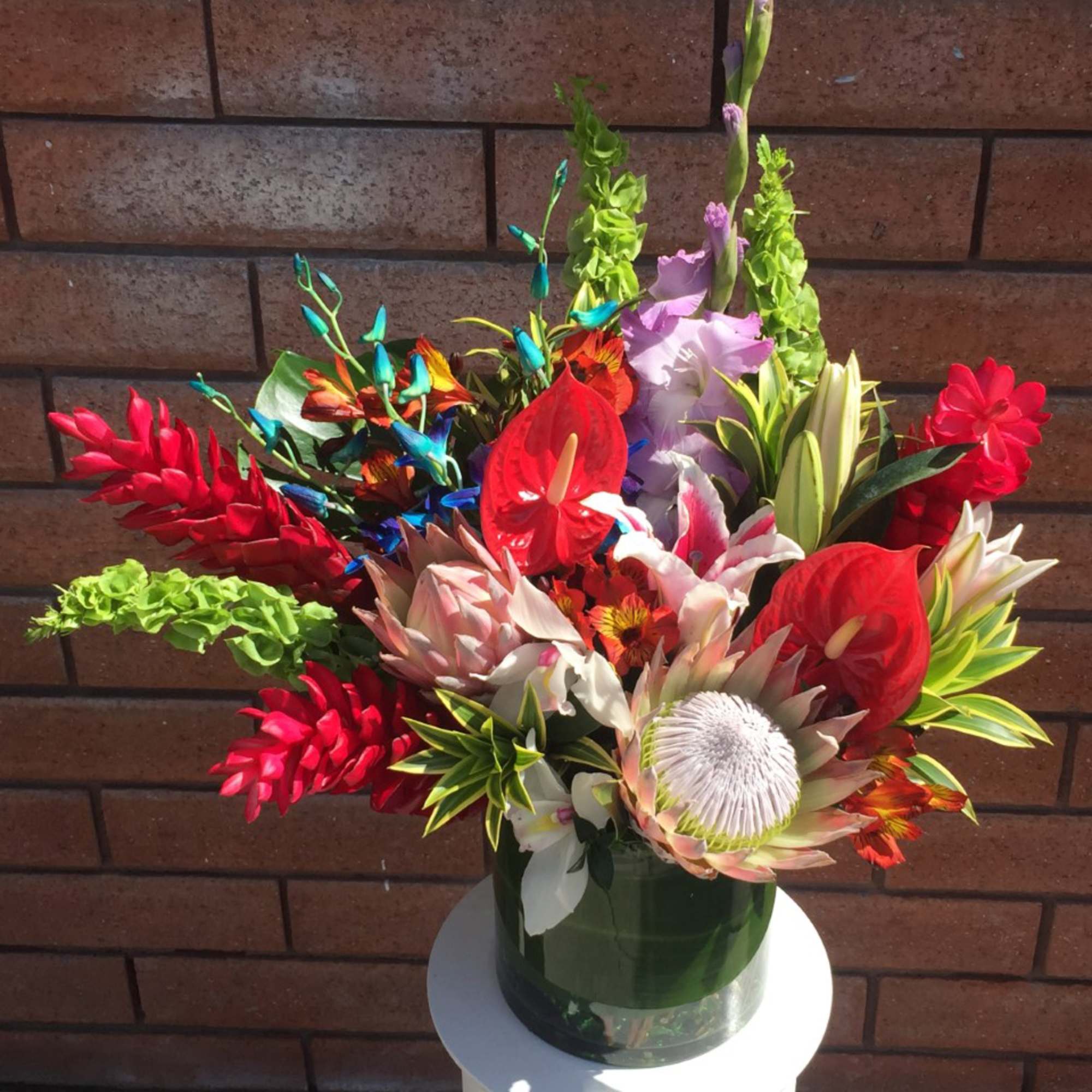 Colorful tropical flower arrangement in a green vase