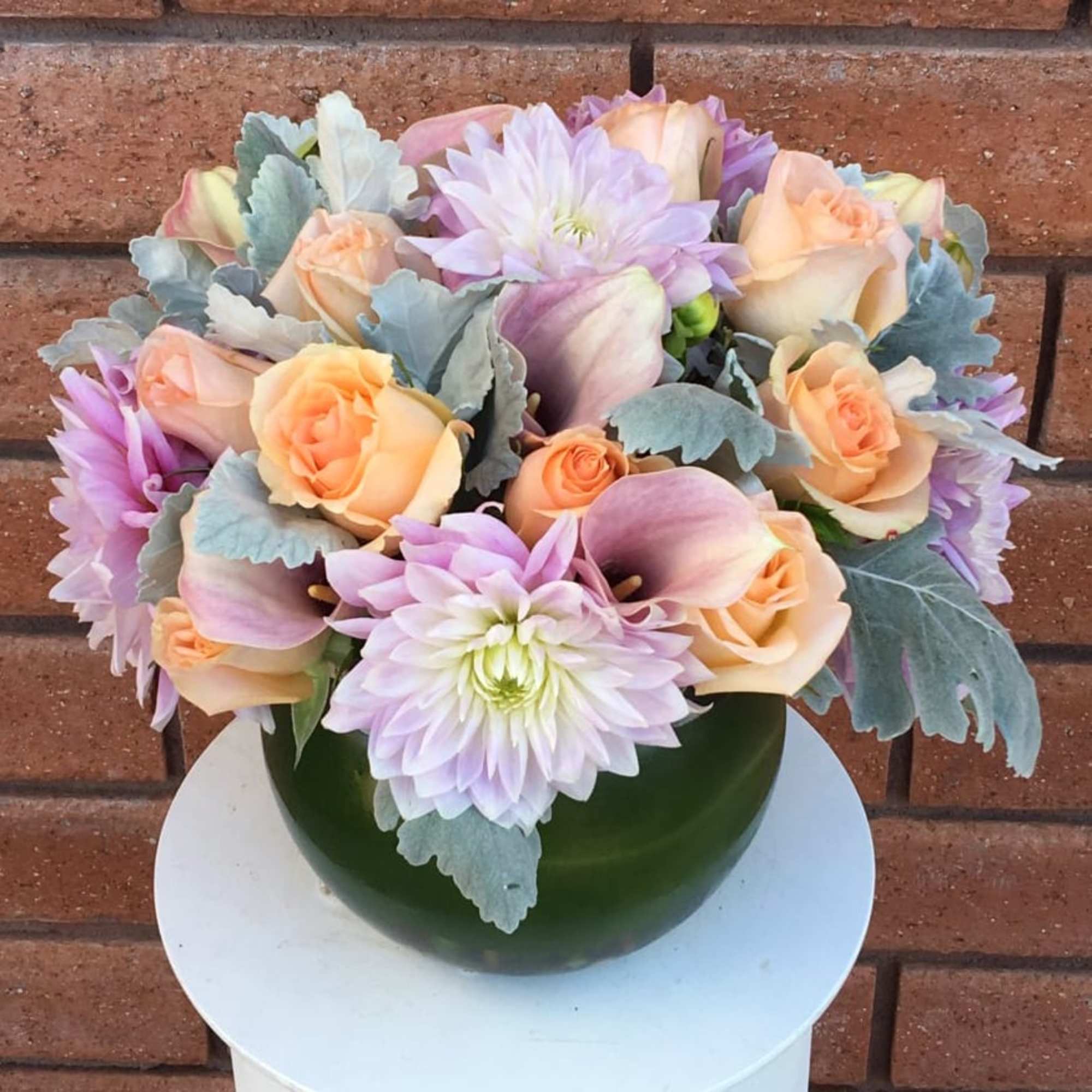 Pastel bouquet of roses, calla lilies, and dahlias in a green vase