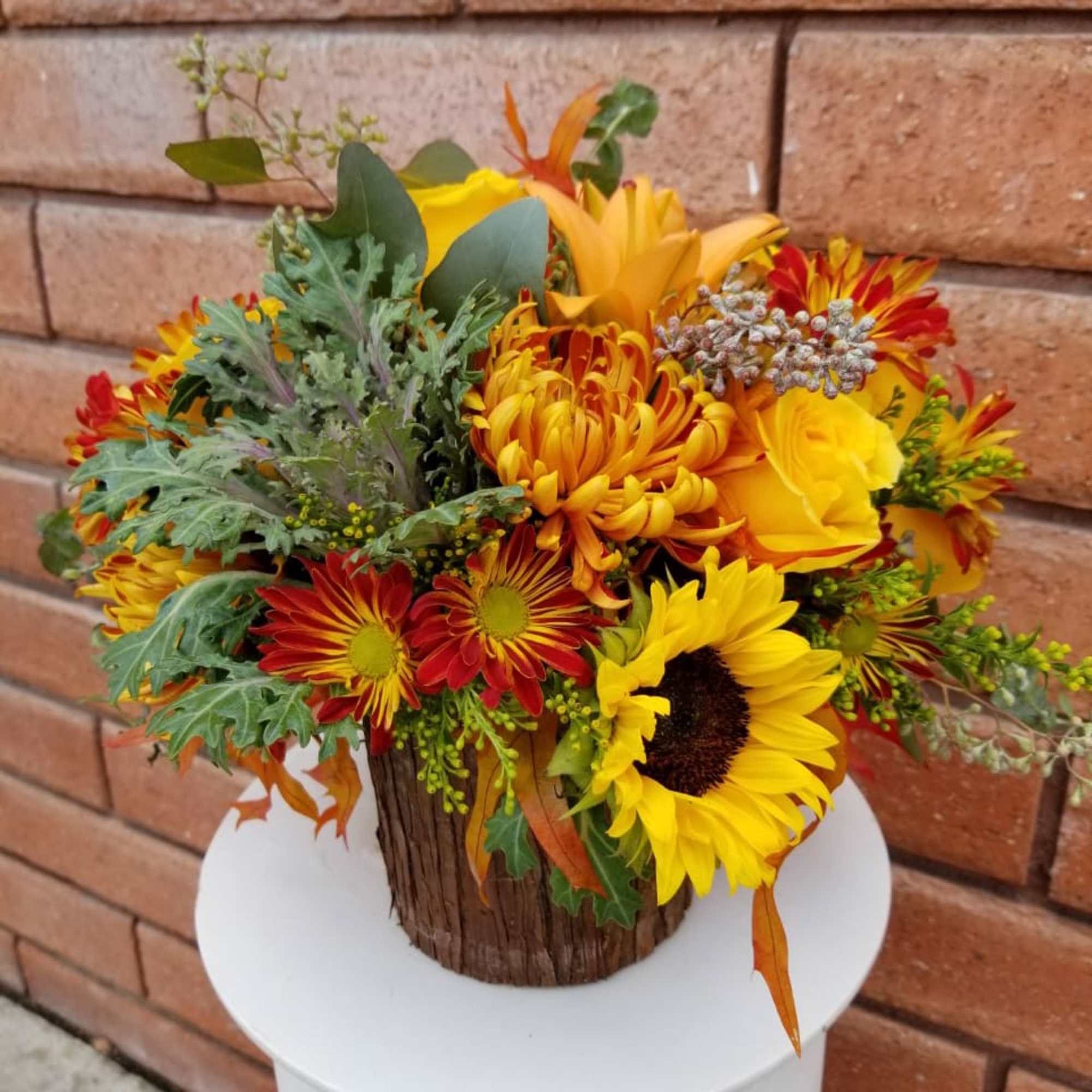 Autumn bouquet with sunflowers and red-orange mums in a rustic wood container
