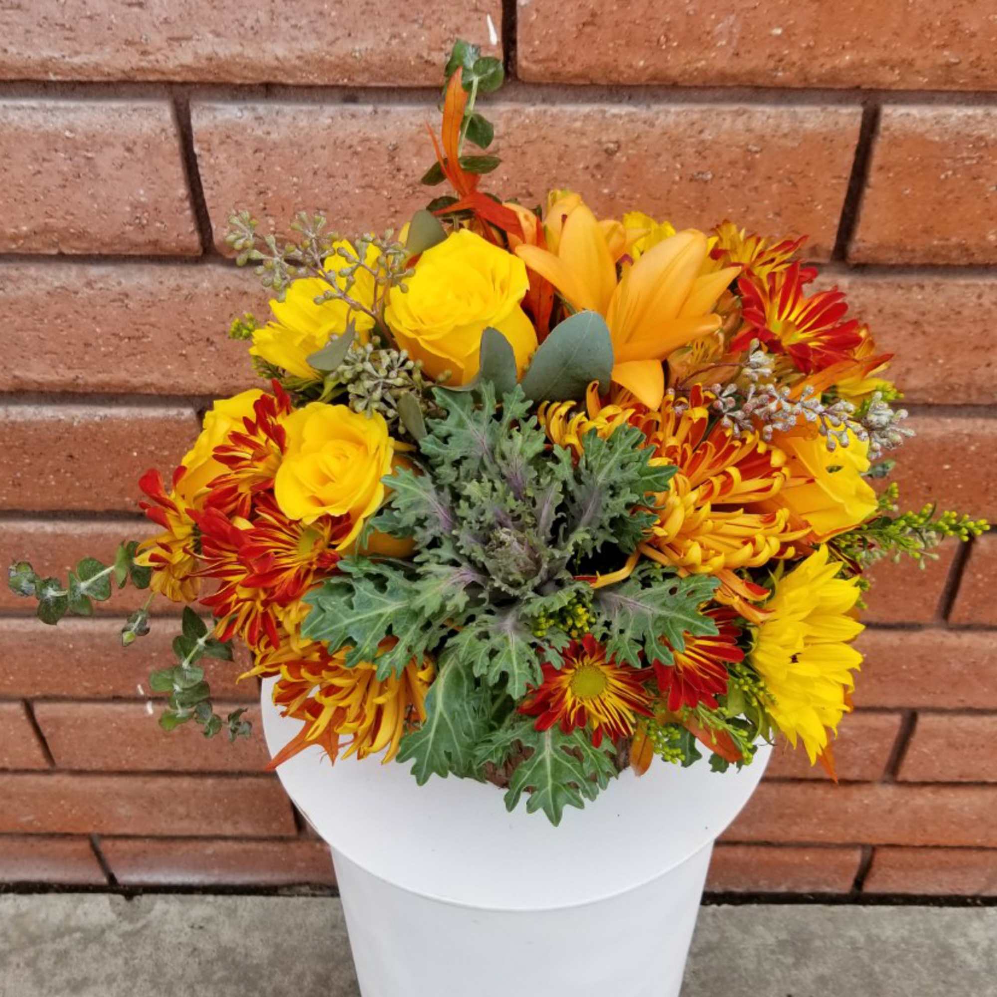 Yellow and red mixed bouquet in a white container