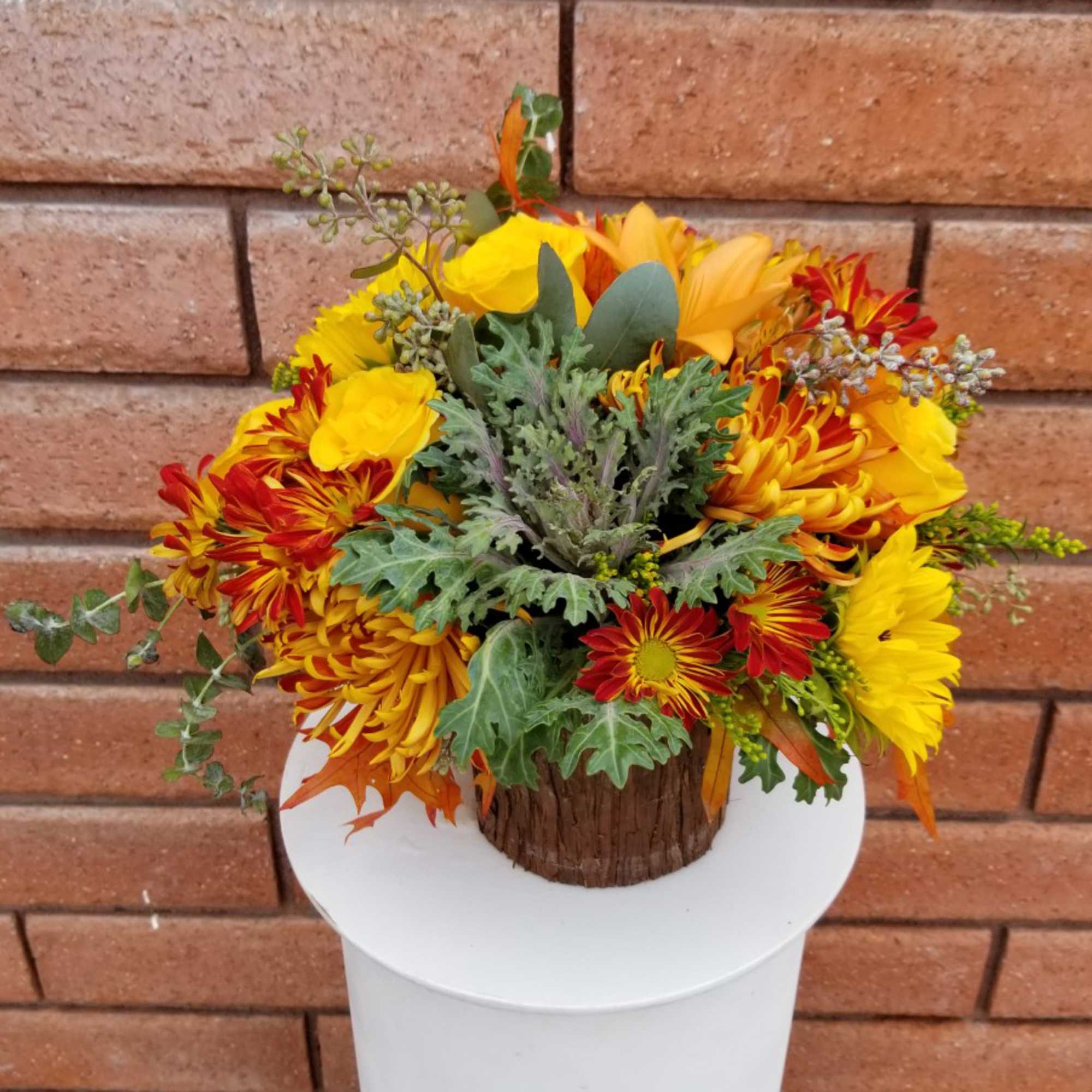 Yellow and red mixed flower arrangement in a rustic wooden container