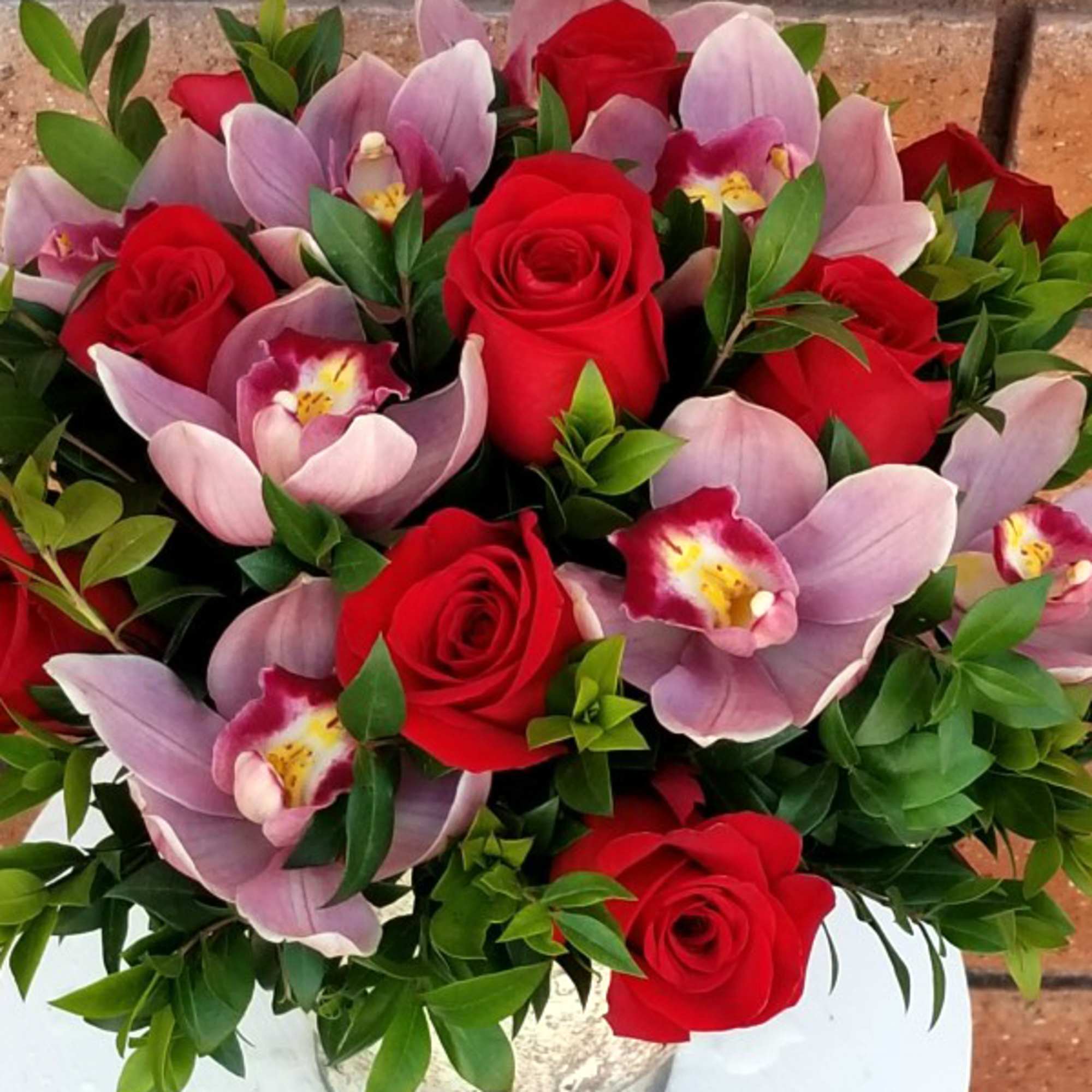 Bouquet of red roses and pink orchids with greenery