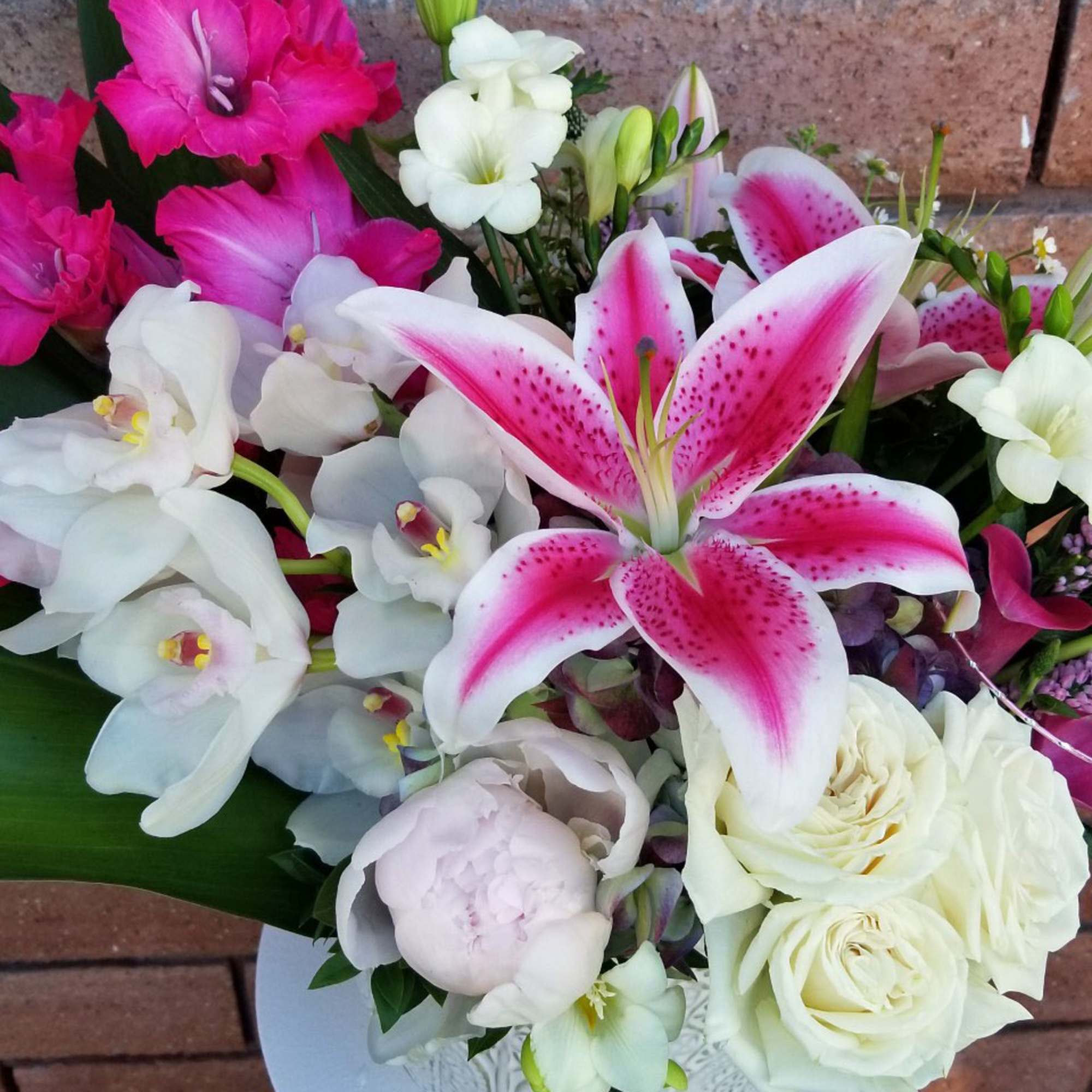 Bouquet of pink lilies, white orchids, and cream roses in a vase