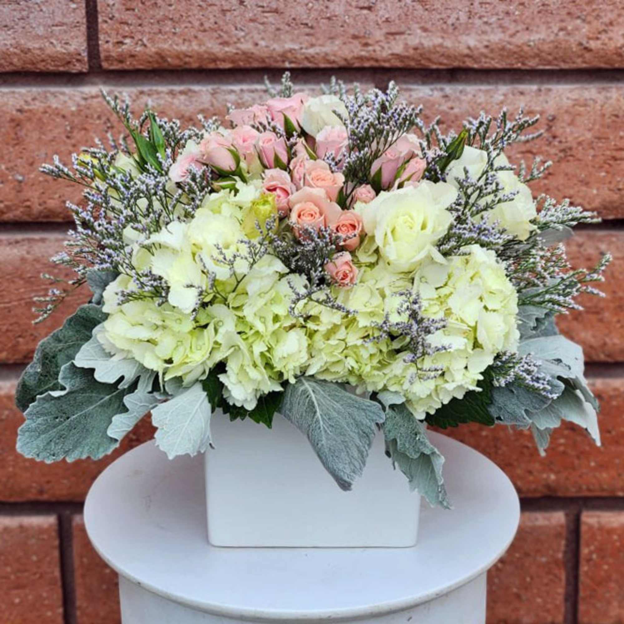 Pastel flower arrangement in a white square vase