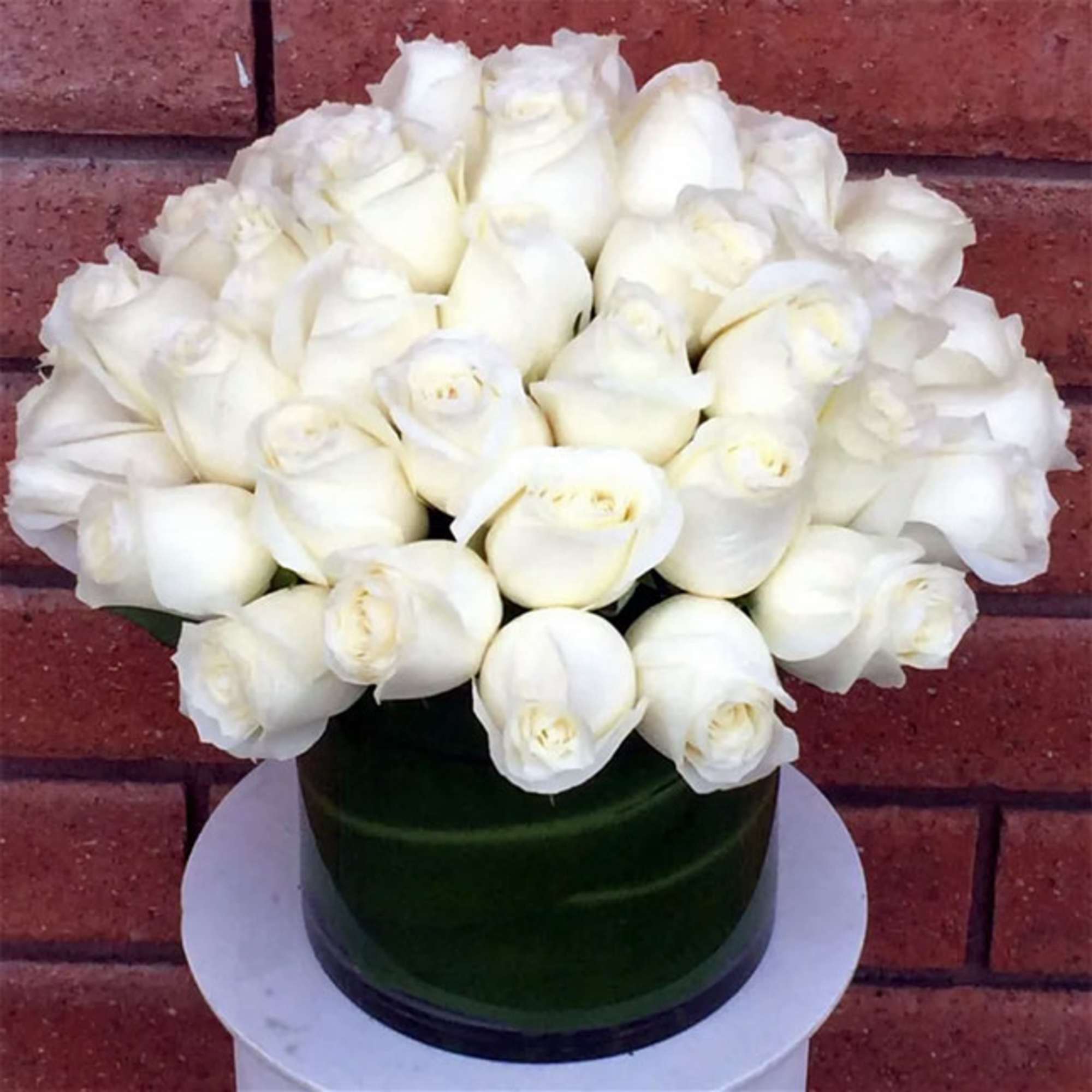 White rose bouquet in a dark green hatbox
