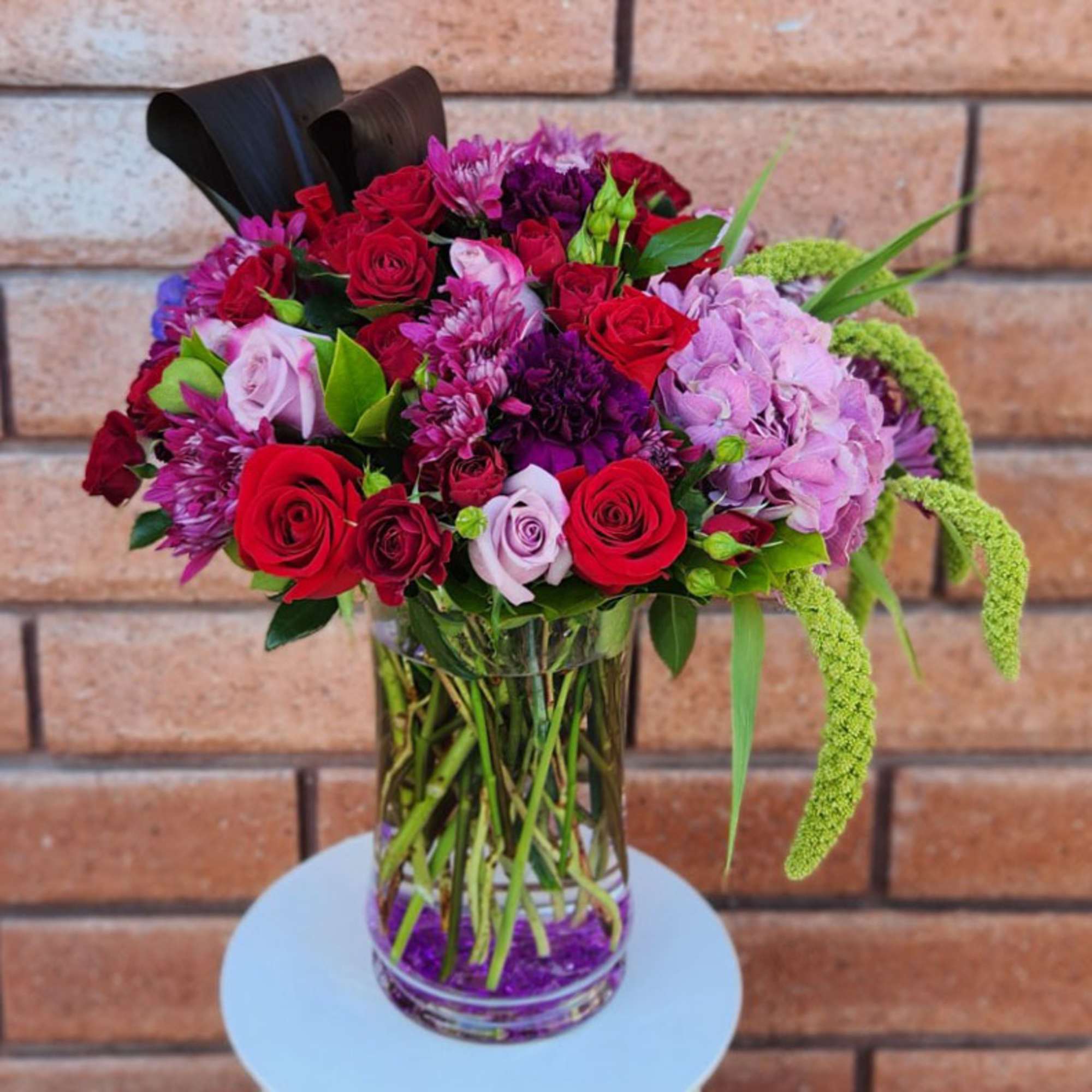Bouquet of red and pink roses with purple blooms in a glass vase