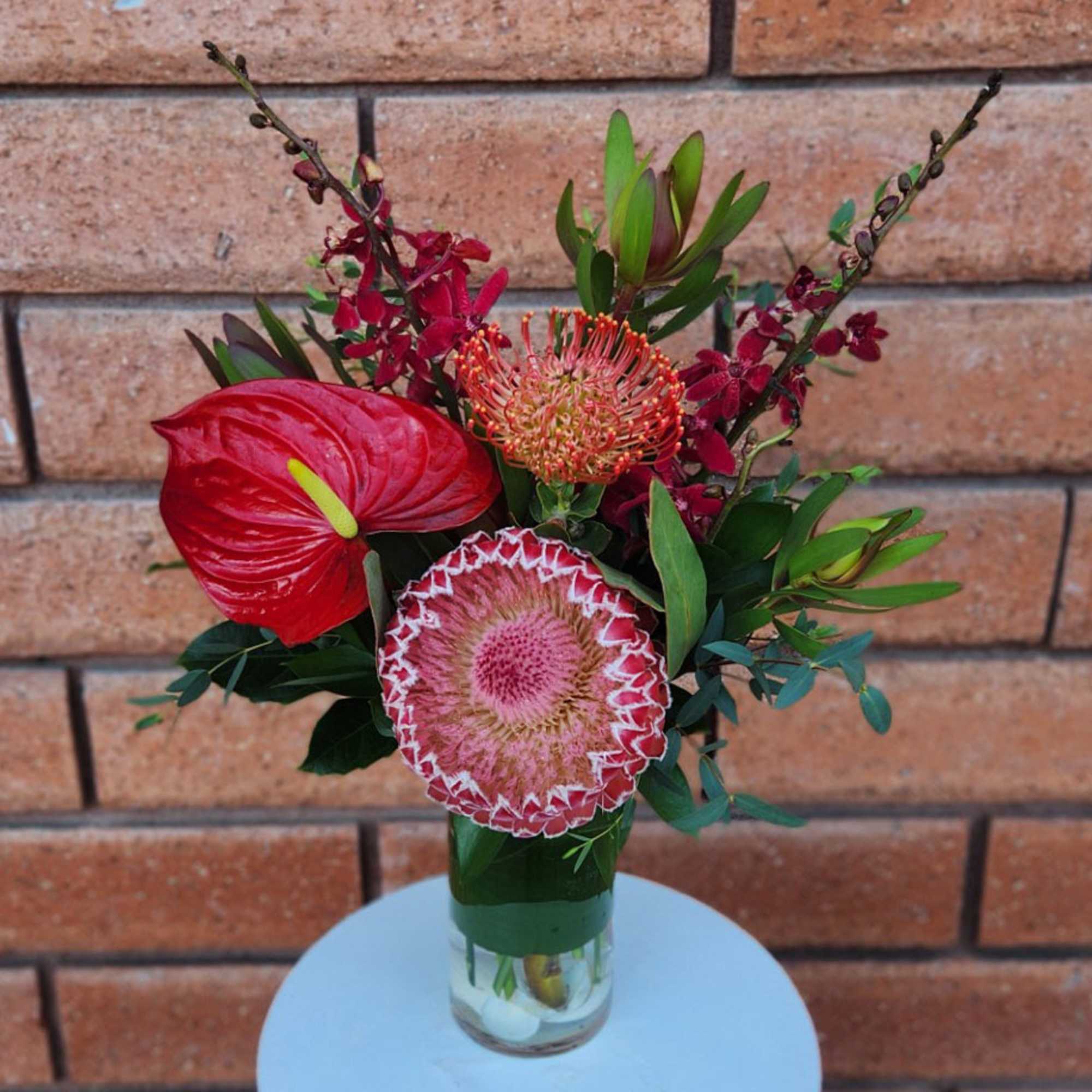 Tropical floral arrangement in a glass vase with red blooms