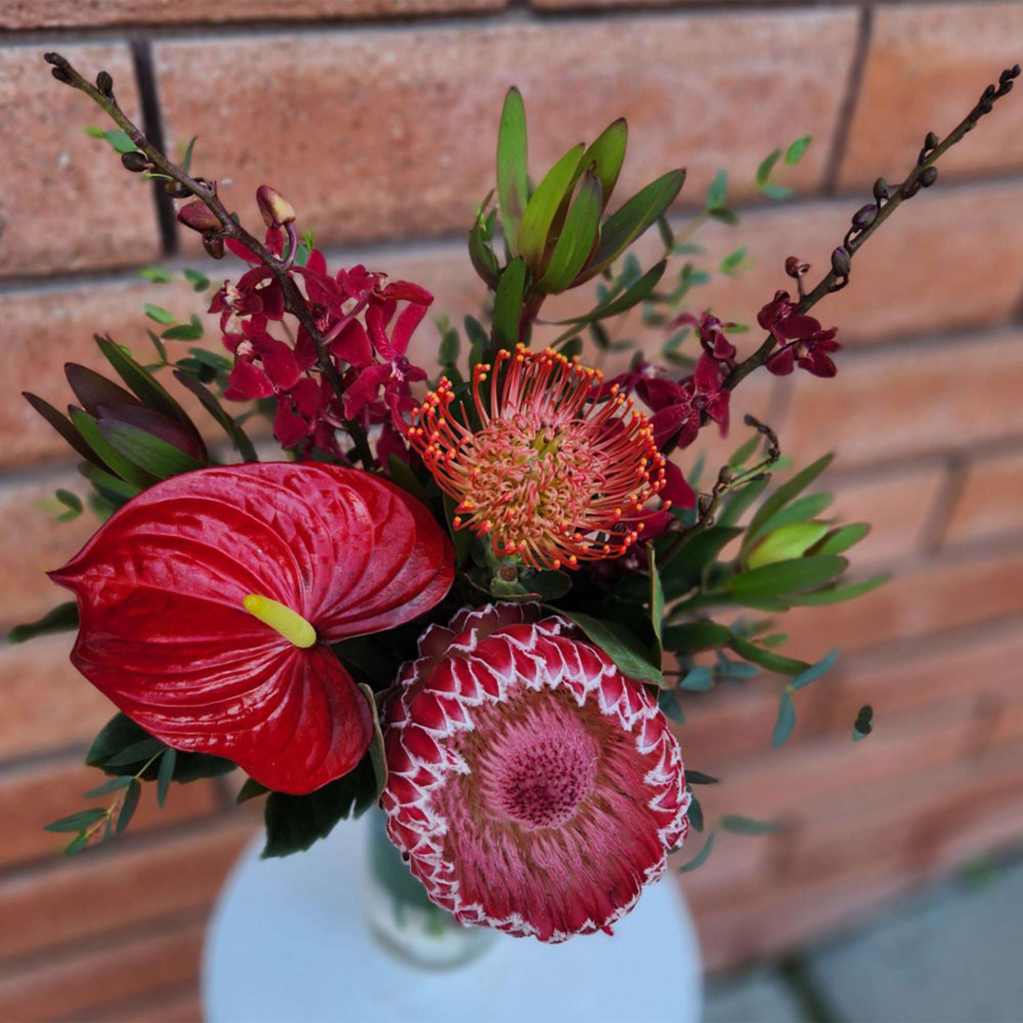 Red tropical flowers arranged in a clear vase