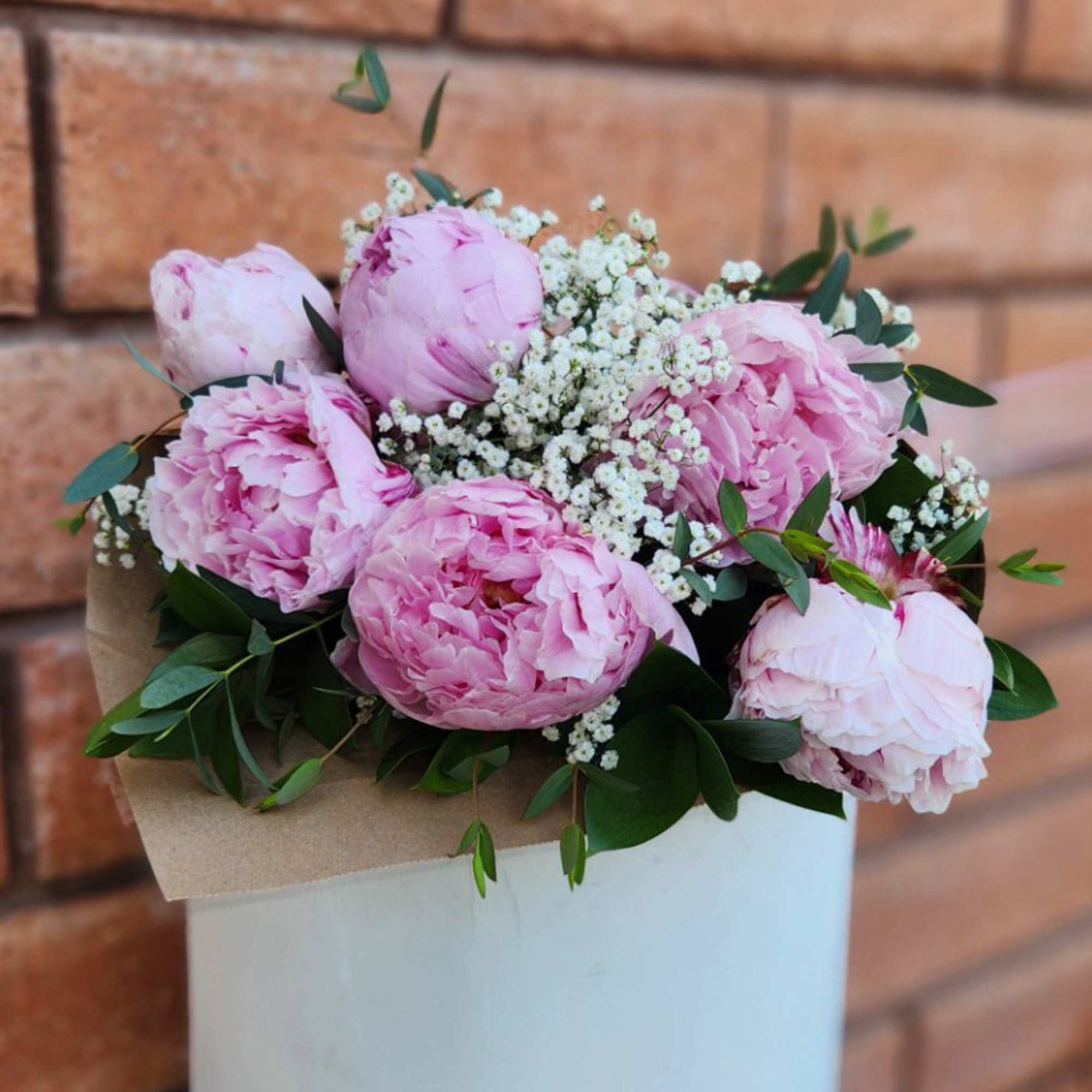 Pink peonies with baby's breath and greenery in a box