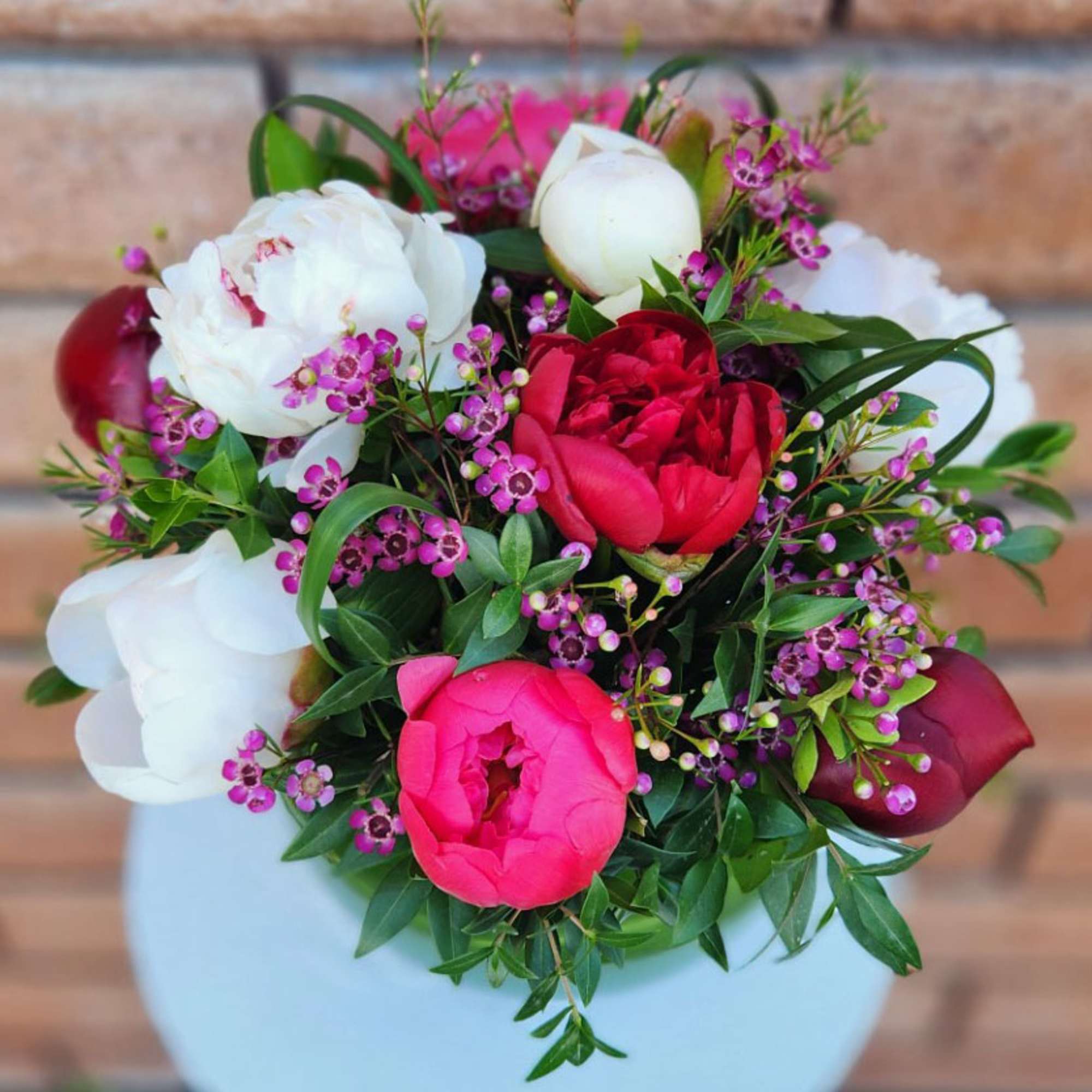 Bouquet of pink, white, and red peonies in a white vase