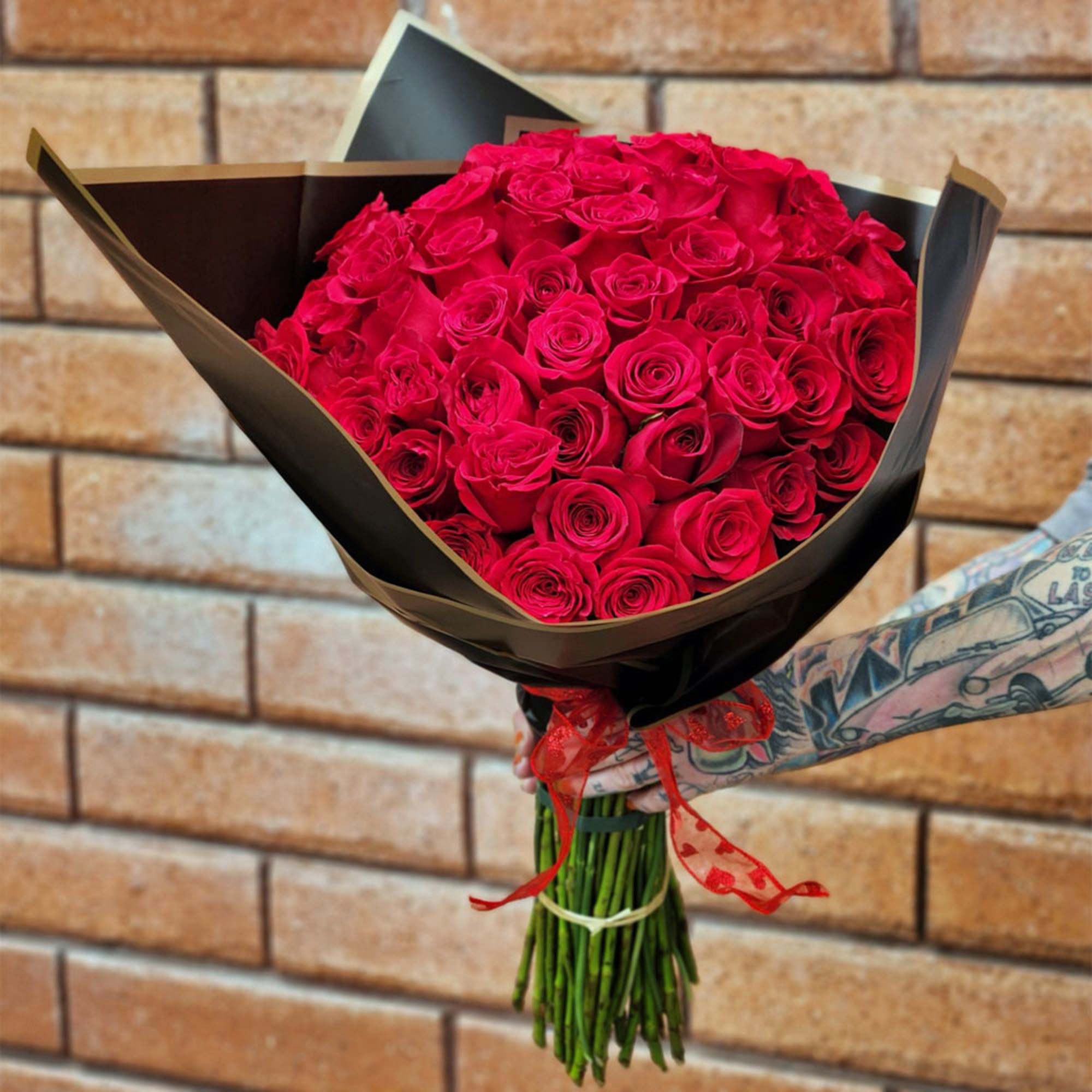 Bouquet of red roses wrapped in black paper with a red ribbon
