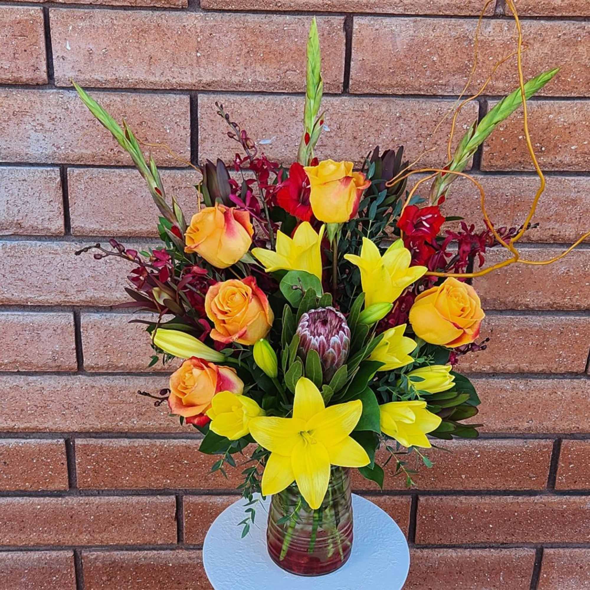 Bouquet of yellow lilies and orange roses in a glass vase, photo 3 of 3