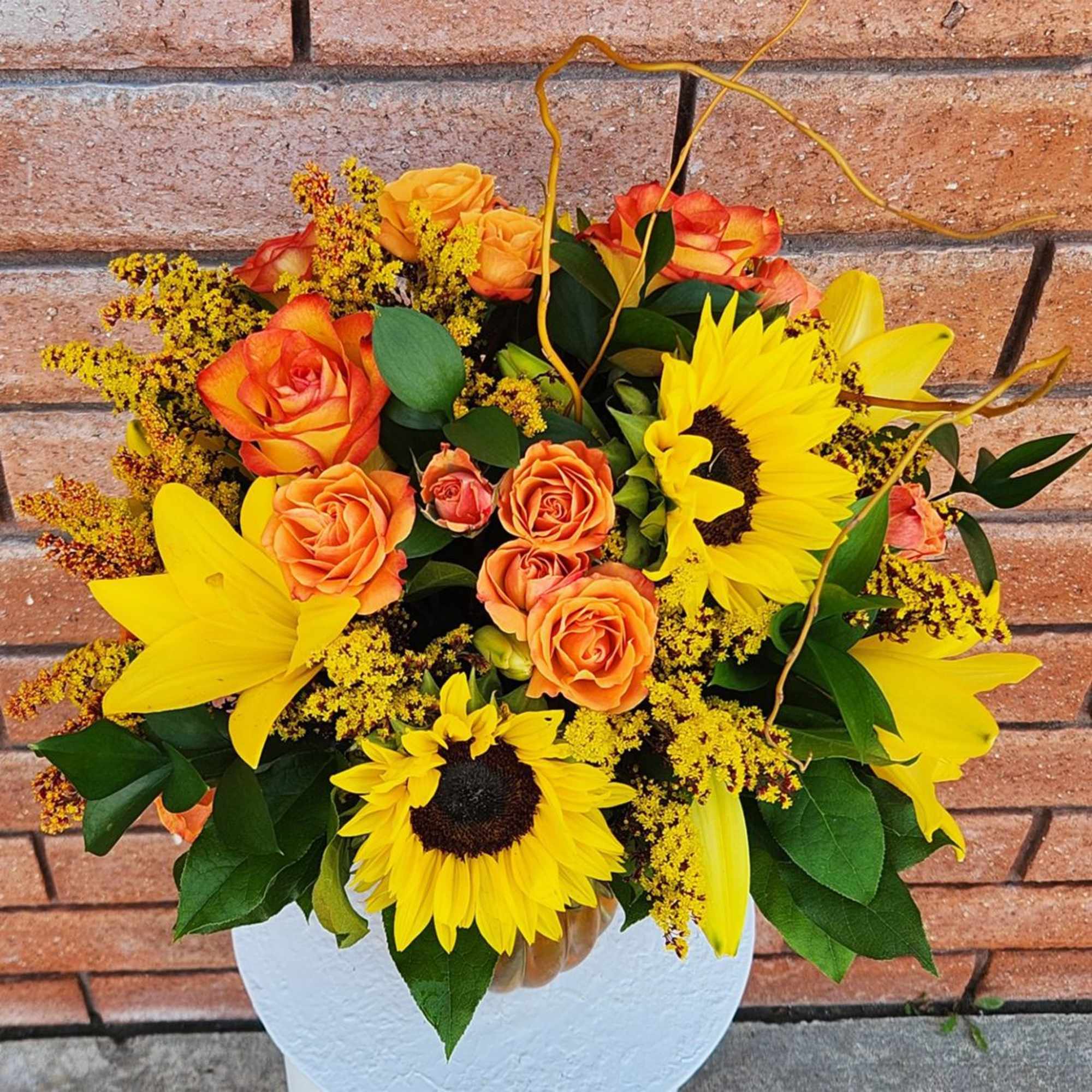 Bouquet of orange roses and yellow sunflowers in a white vase