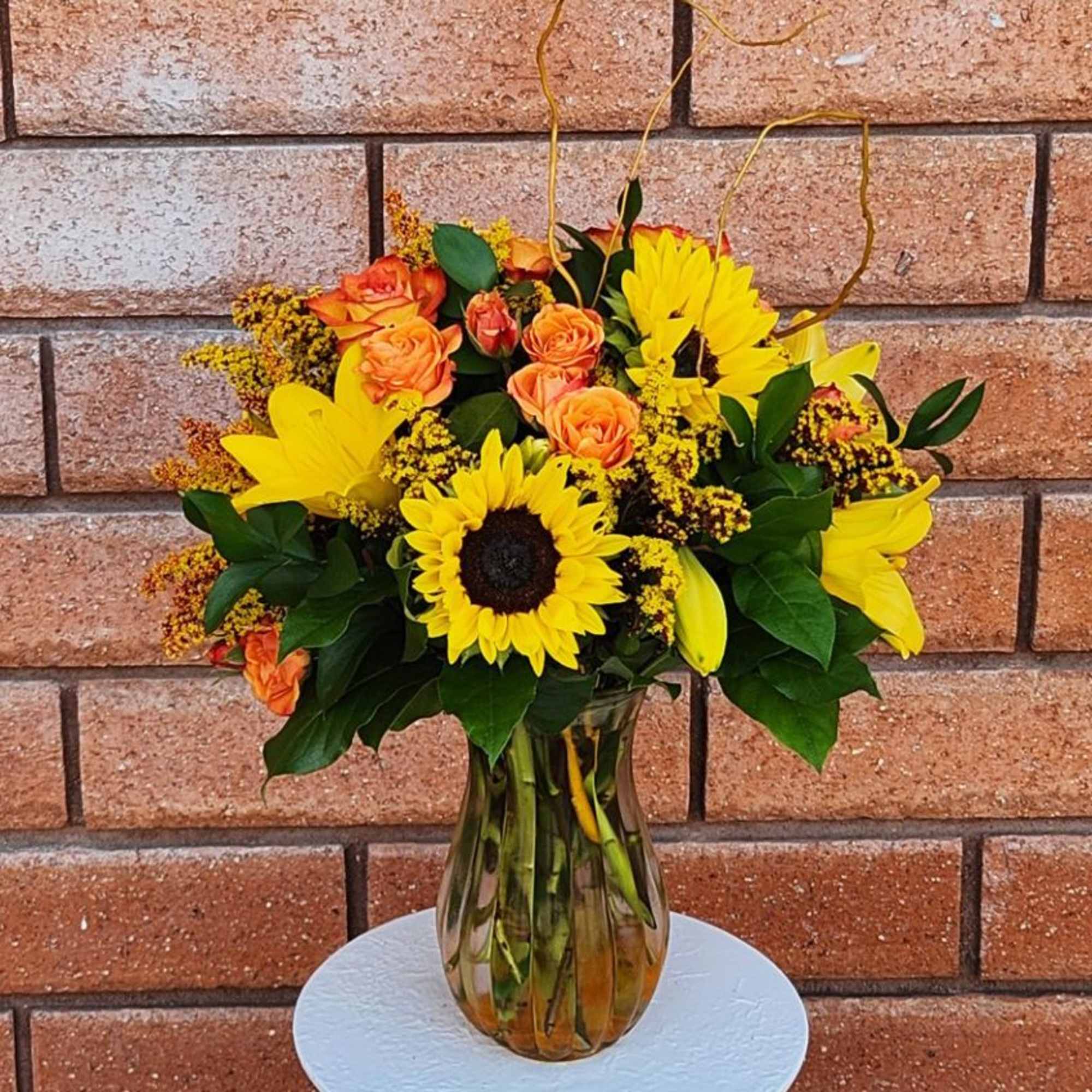 Bouquet of sunflowers and orange roses in a glass vase