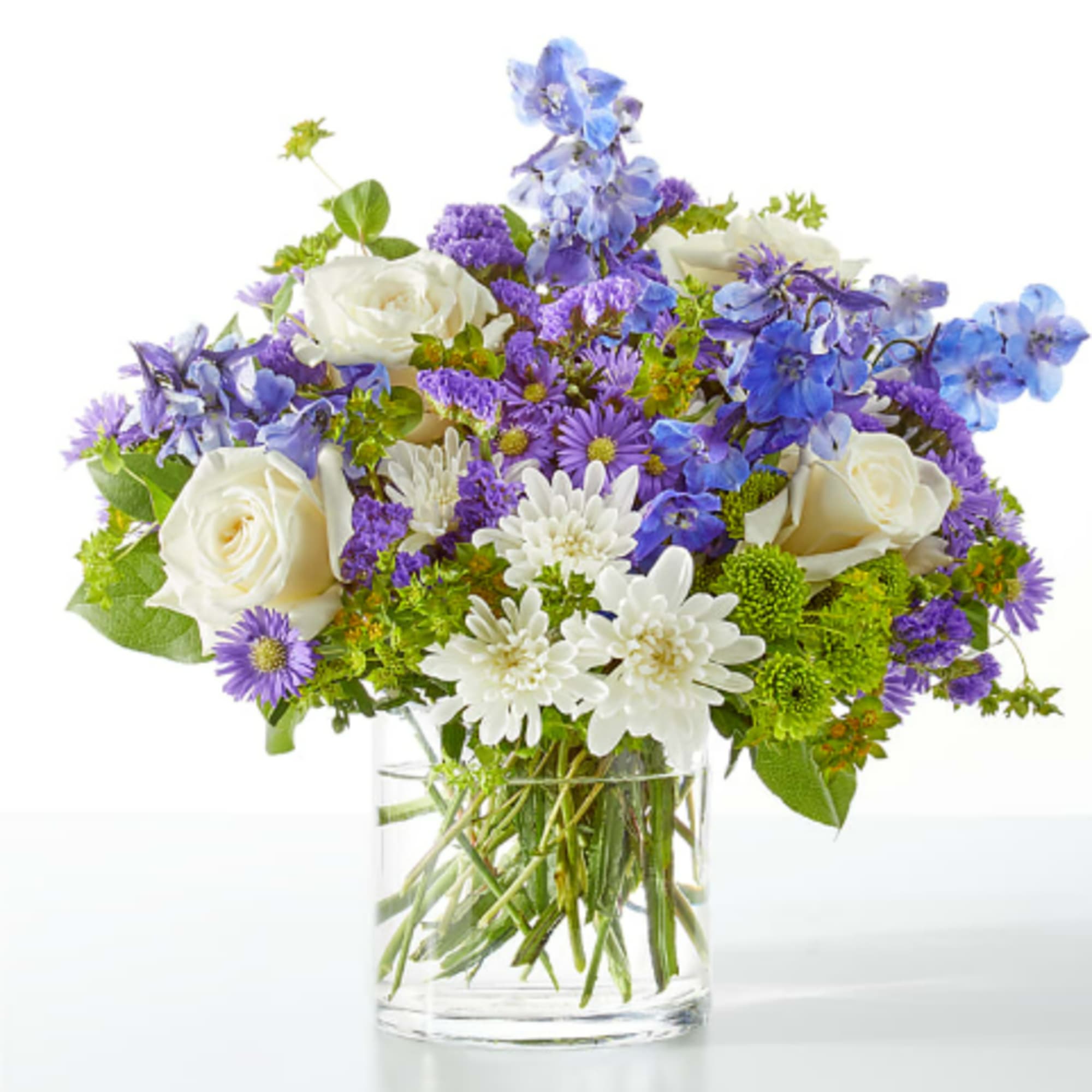 White roses and purple-blue flowers in a clear glass vase