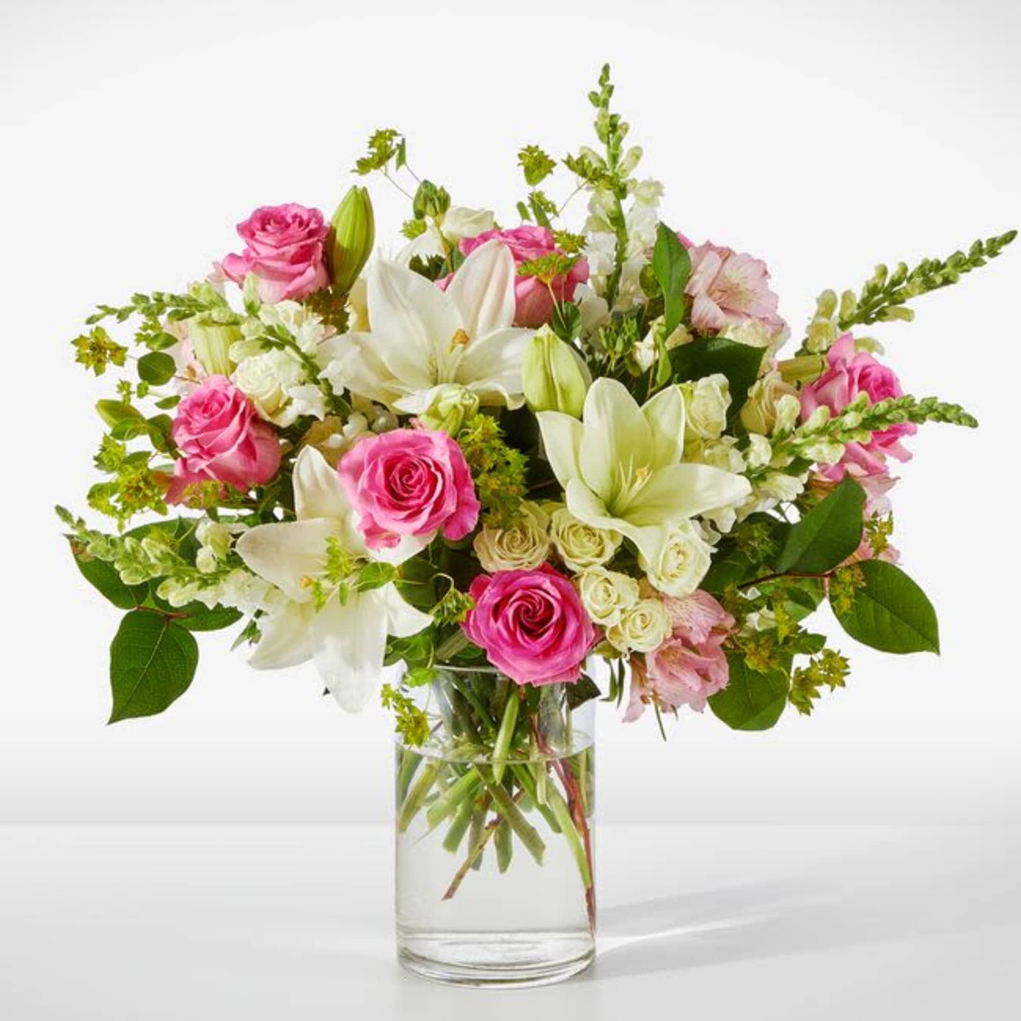 Pink roses and white lilies arranged in a clear glass vase