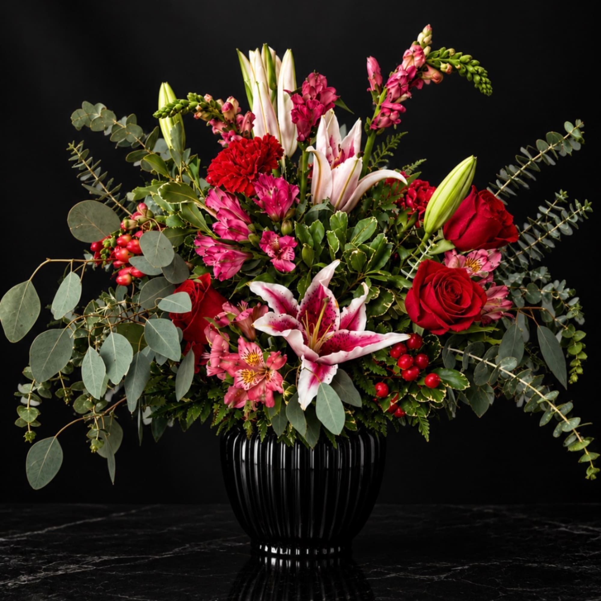 Red roses, pink lilies, and mixed greenery in a black vase