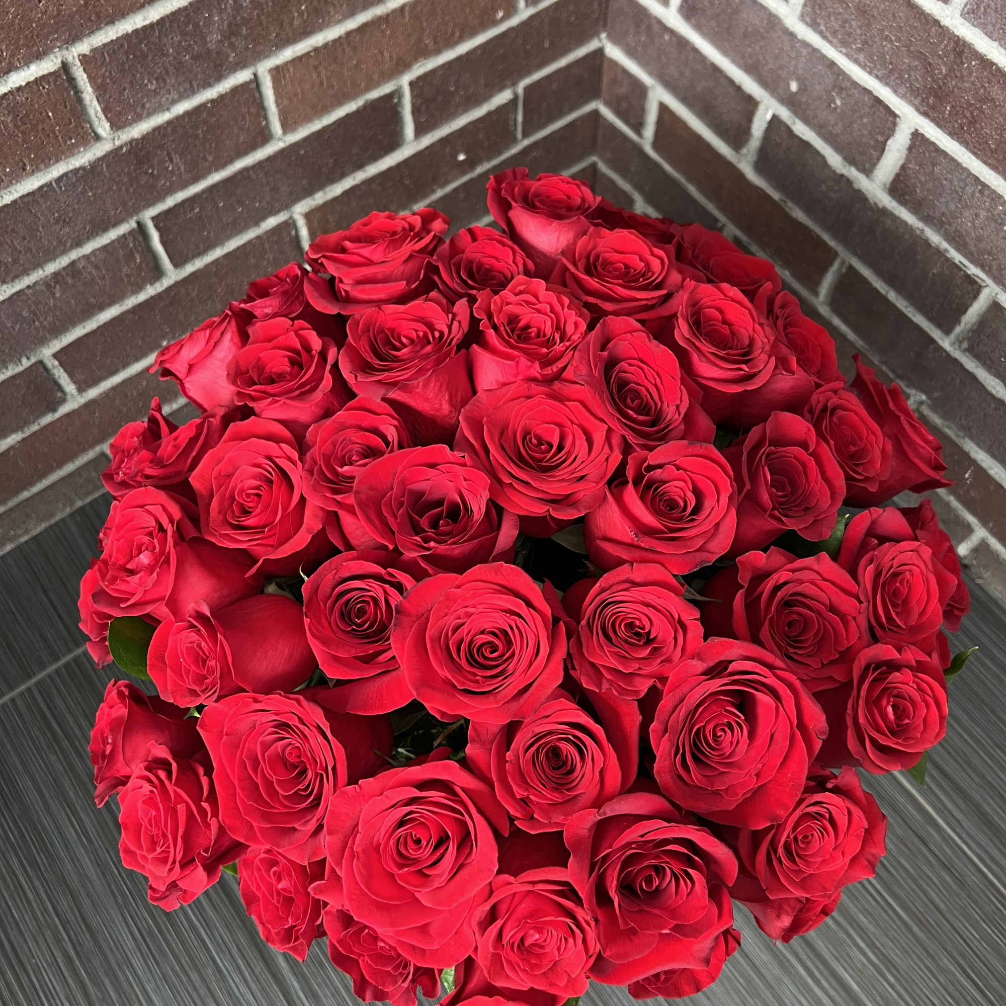 Large bouquet of red roses against a brick wall