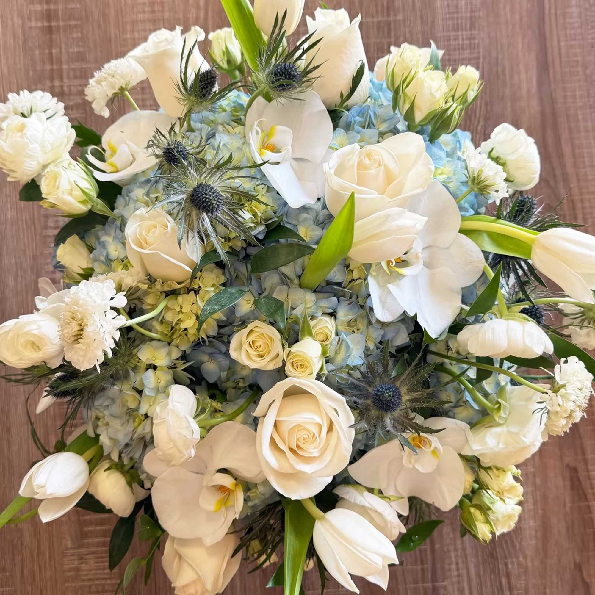 White roses and orchids with blue hydrangeas in a bouquet