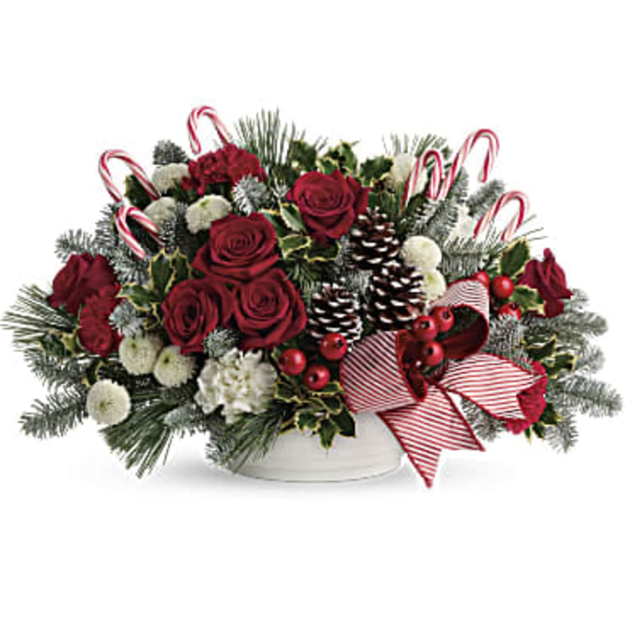 Christmas arrangement with red roses, pinecones, and candy canes in a white bowl