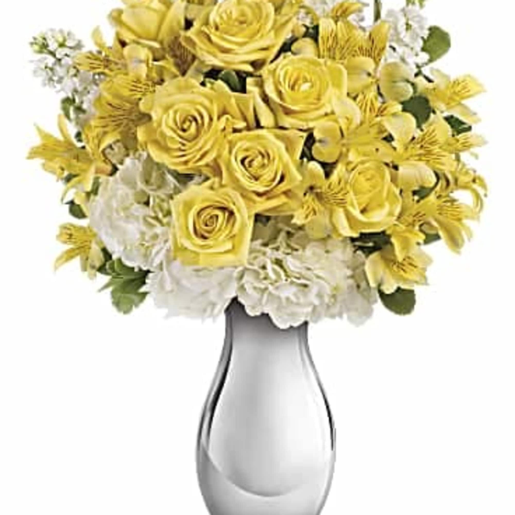 Yellow roses and white flowers arranged in a clear glass vase