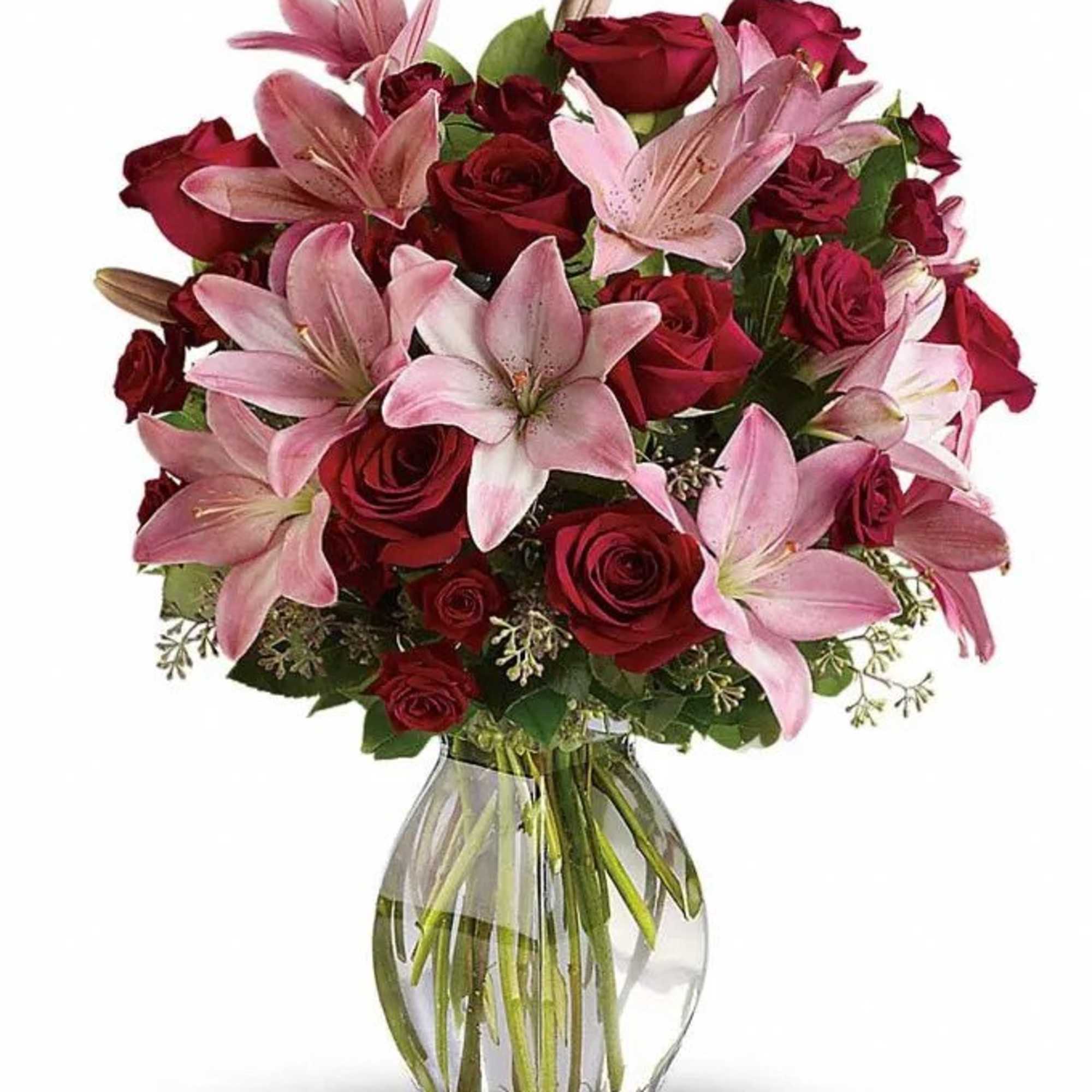 Red roses and pink lilies arranged in a clear glass vase