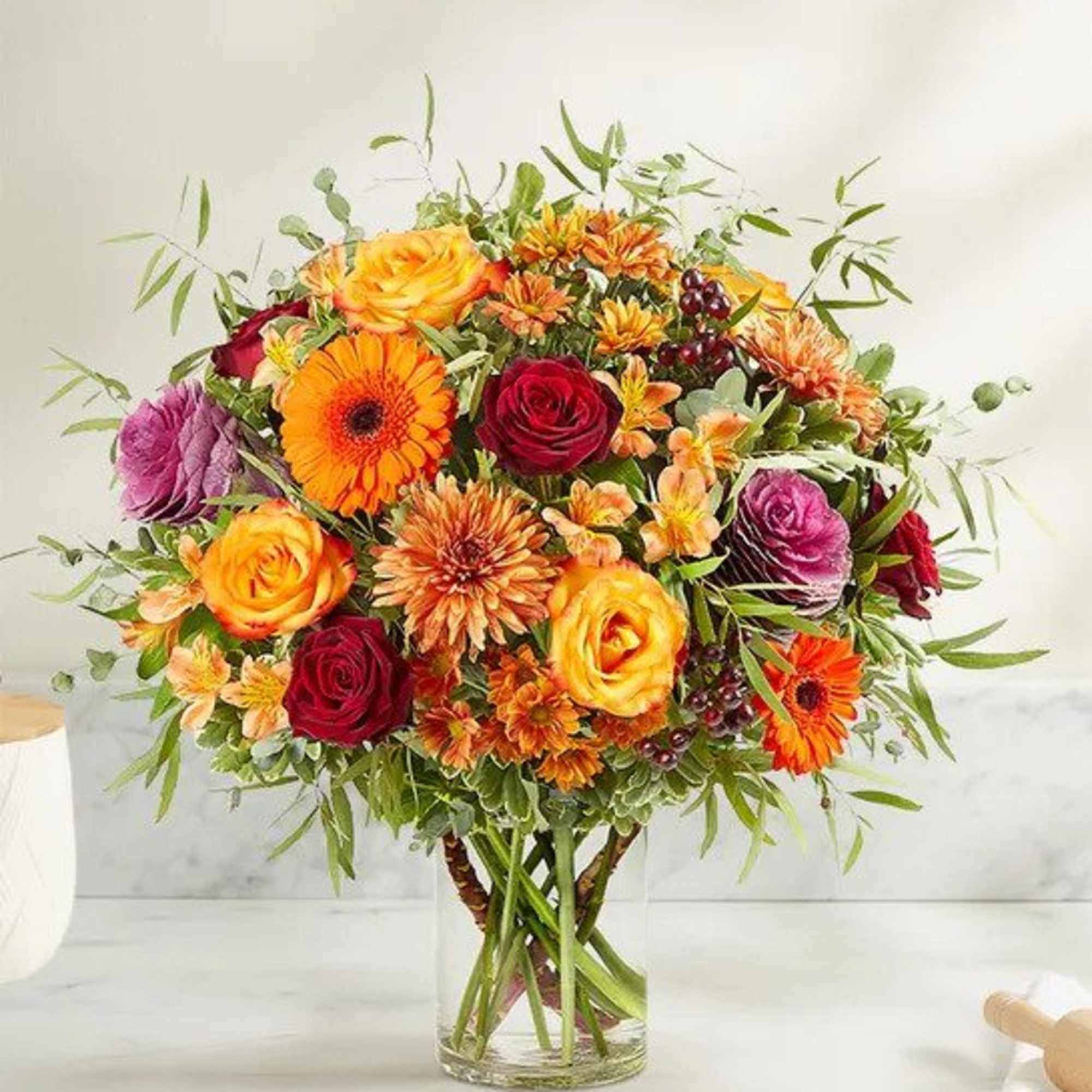 Mixed bouquet of roses and gerbera daisies in a clear glass vase