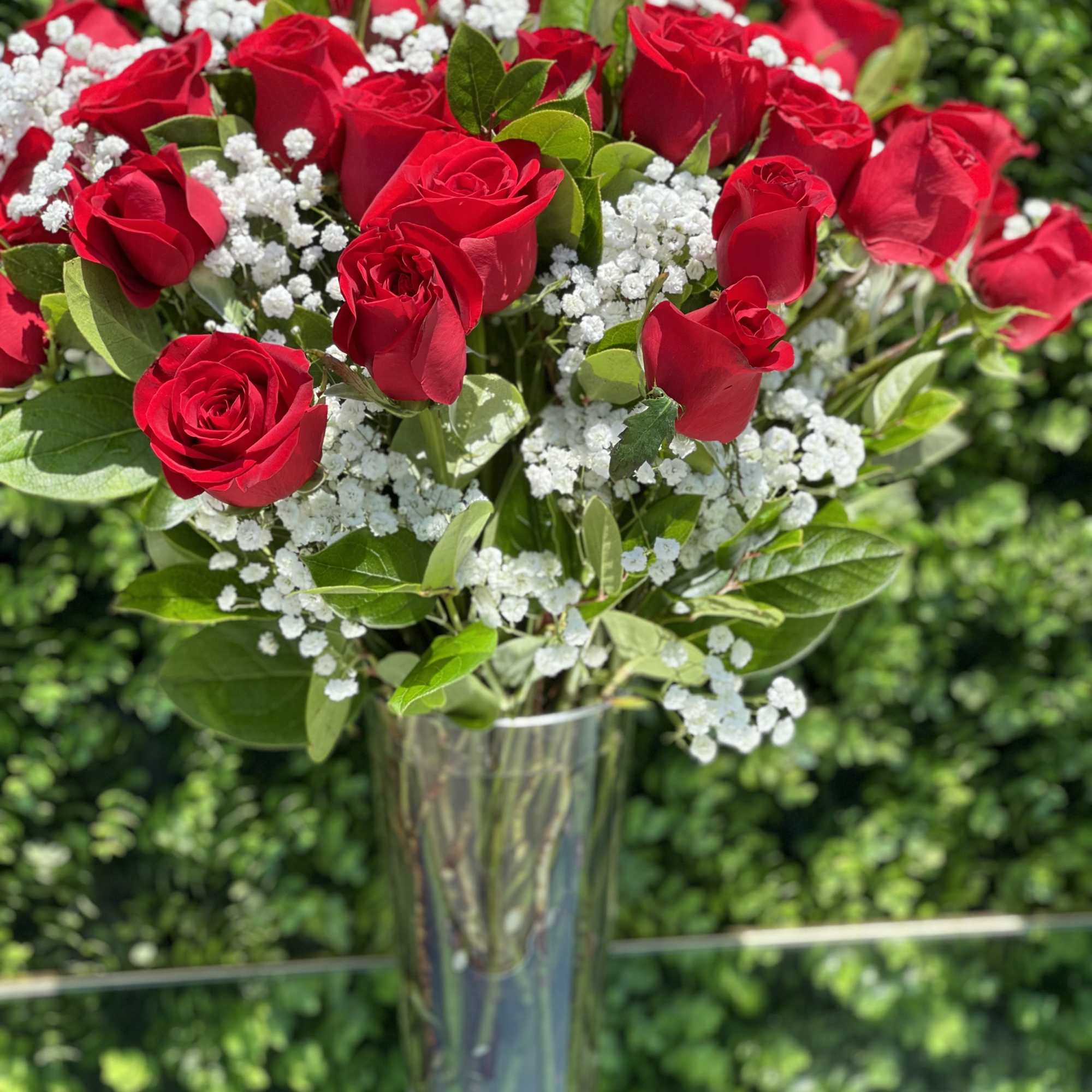 Red roses with white baby's breath in a clear glass vase
