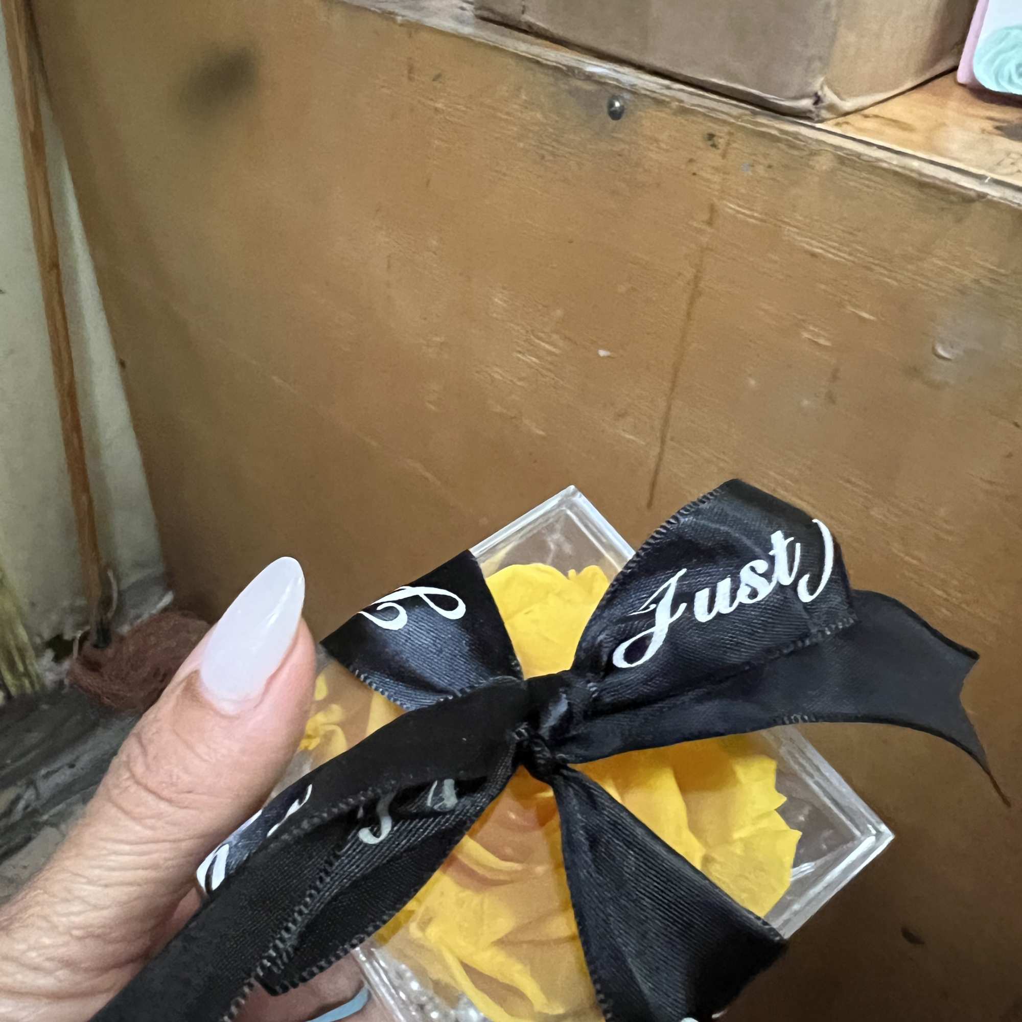 Small clear gift box with yellow flowers tied with a black ribbon