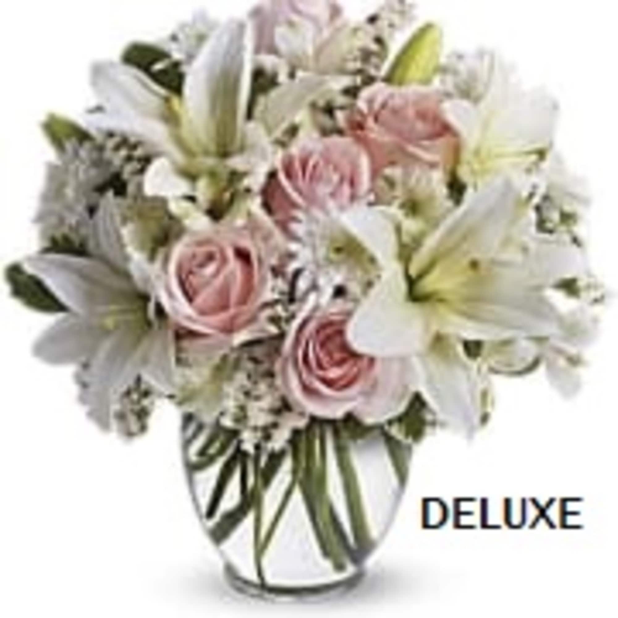 Arrangement of white lilies and pale pink roses in a clear glass vase