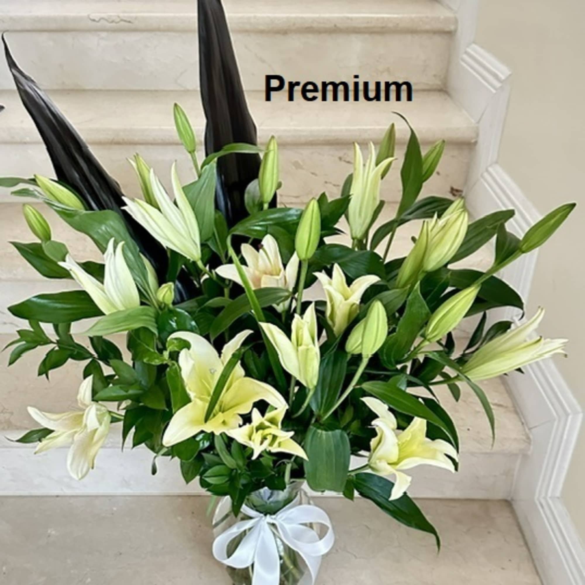 Bouquet of white lilies in a glass vase with a white ribbon