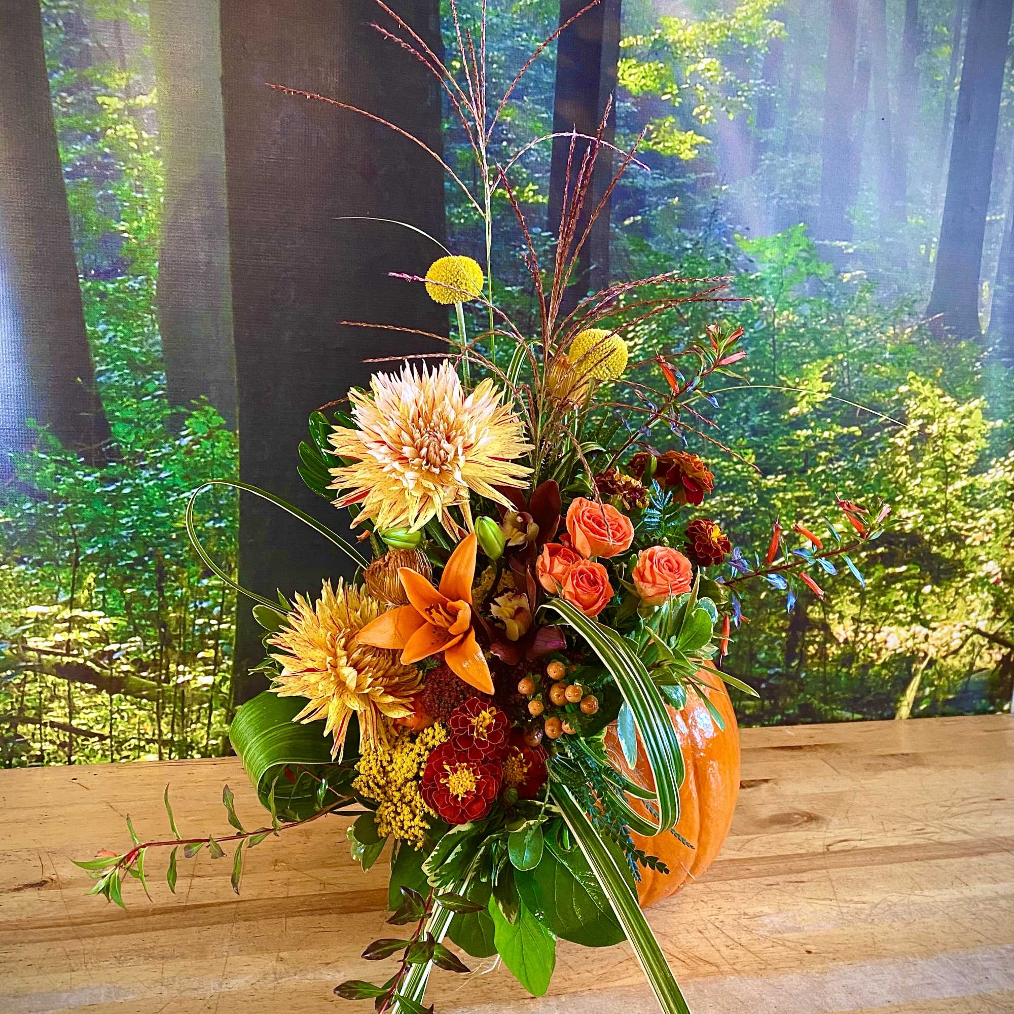 Tall autumn bouquet with orange and yellow flowers in a pumpkin vase