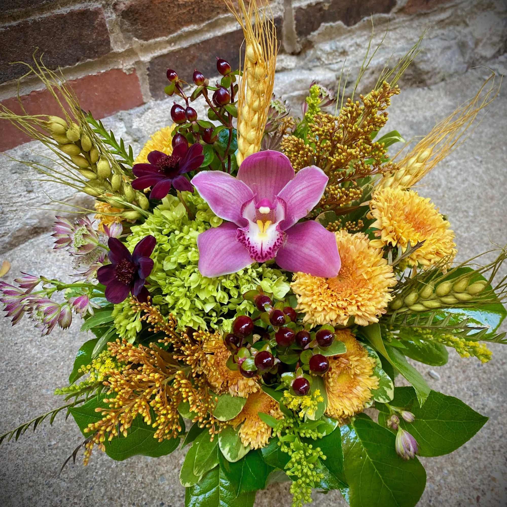 Mixed bouquet with pink orchid, yellow mums, and wheat stems