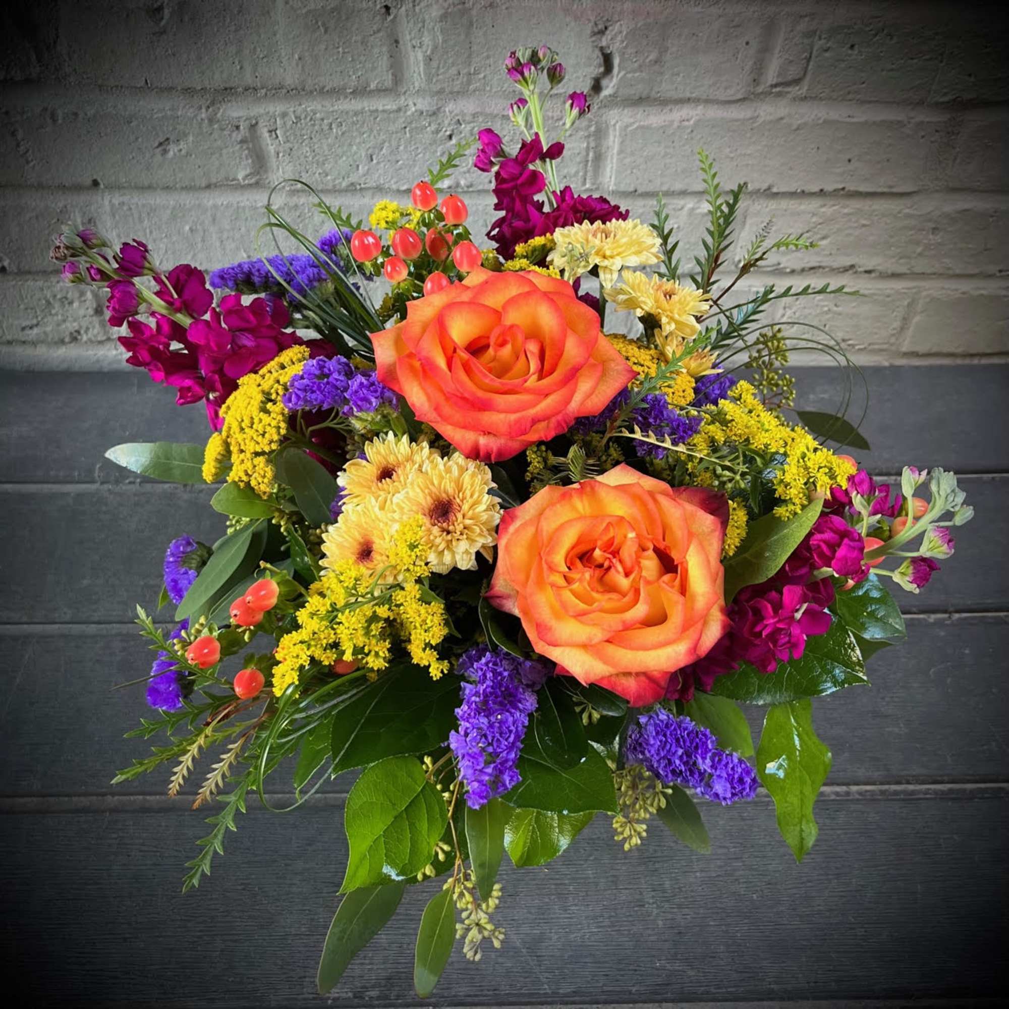 Two large orange roses anchor this Tuscan Sunset bouquet, a vibrant flower