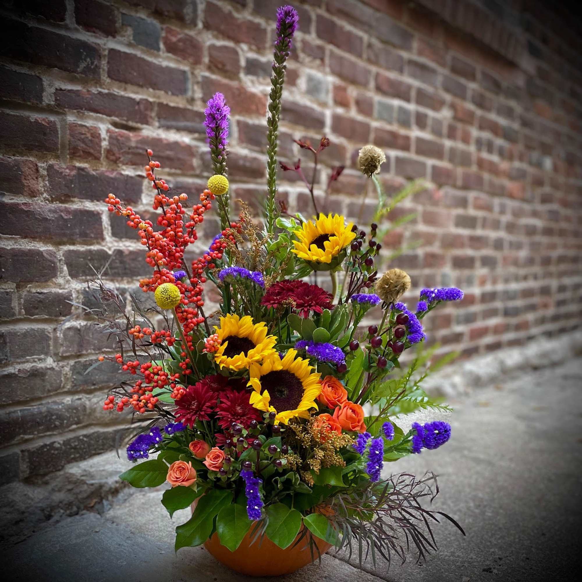Colorful mixed flower arrangement in a low orange container
