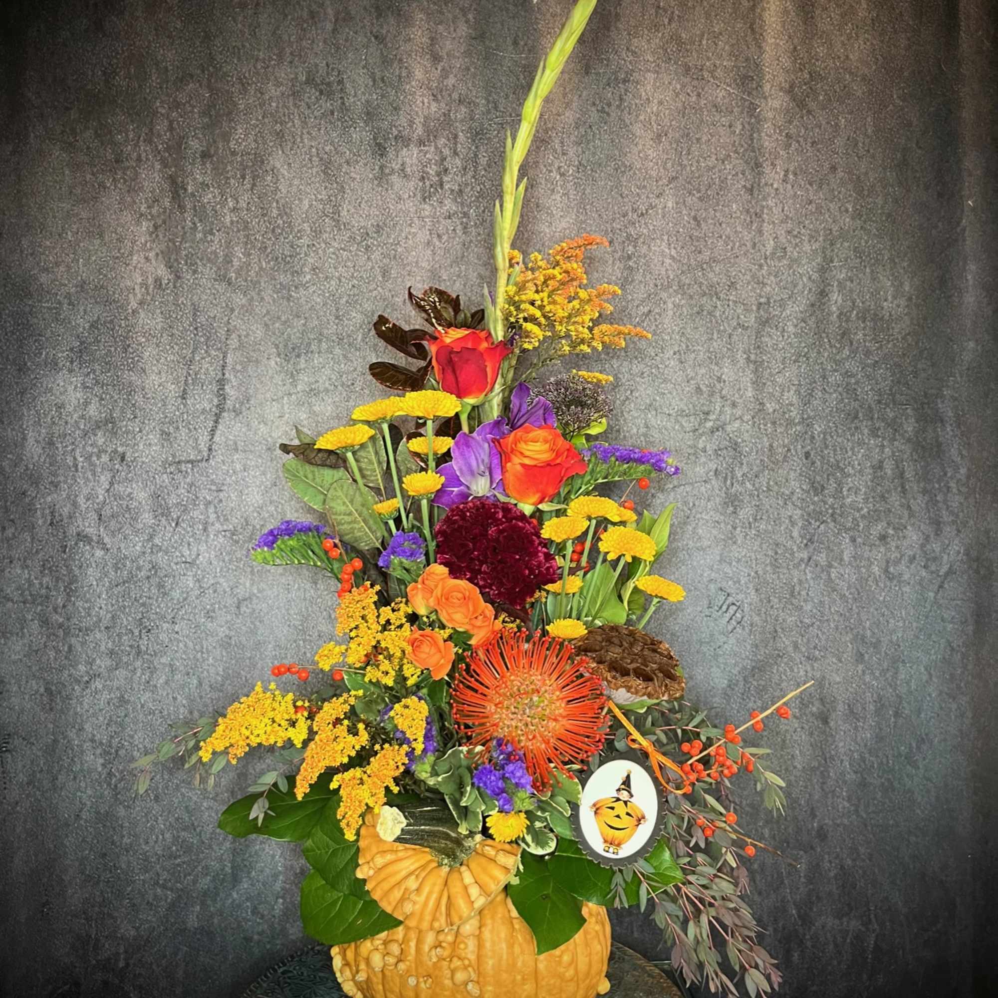 Autumn floral arrangement in a pumpkin container with orange and purple blooms