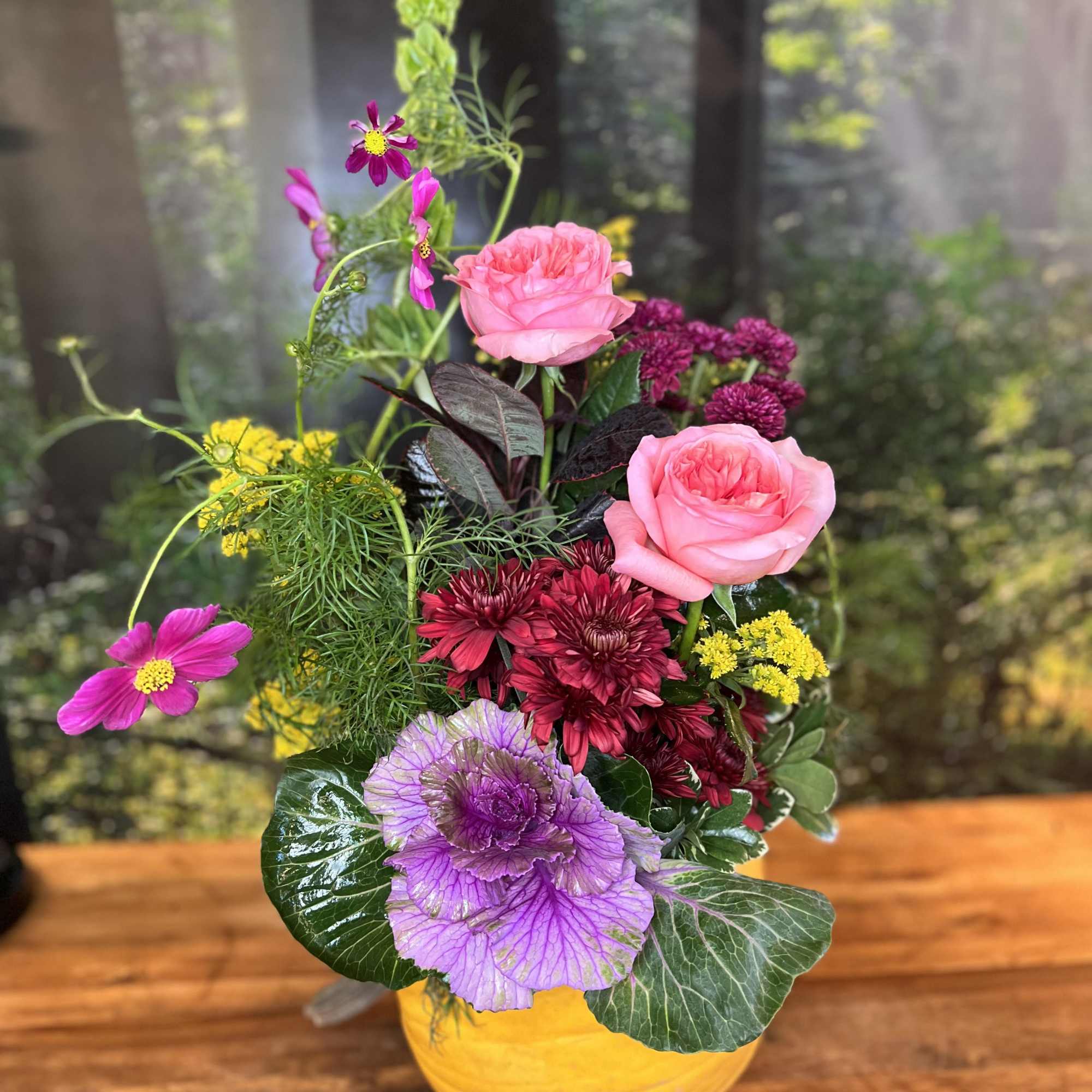 Mixed pink, purple, and yellow flowers arranged in a yellow vase