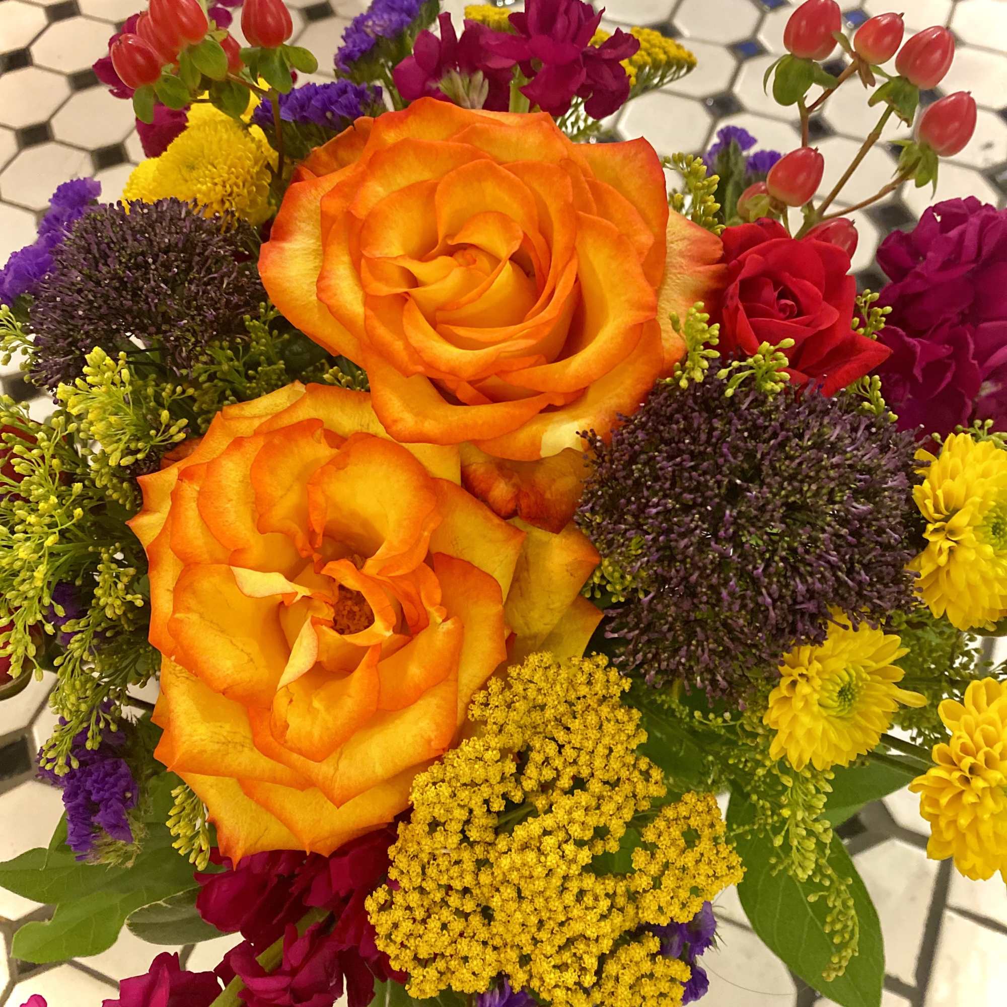 Bouquet of orange and red roses with yellow and purple filler flowers