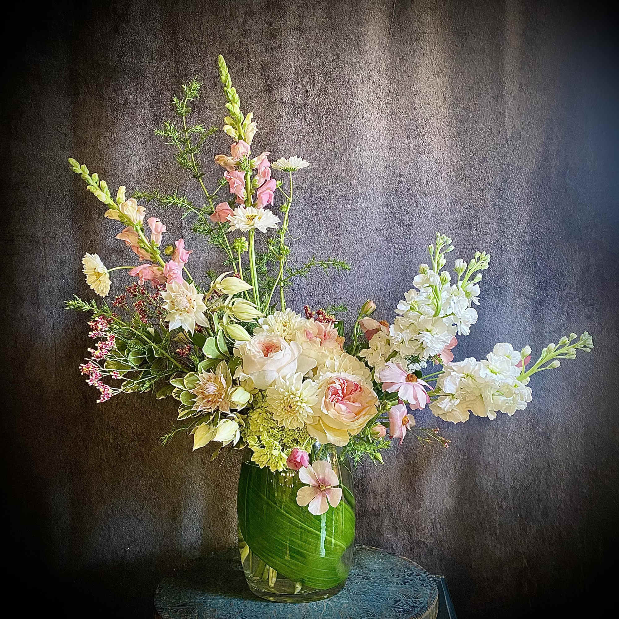 Tall mixed floral arrangement in a glass vase with pink and white blooms