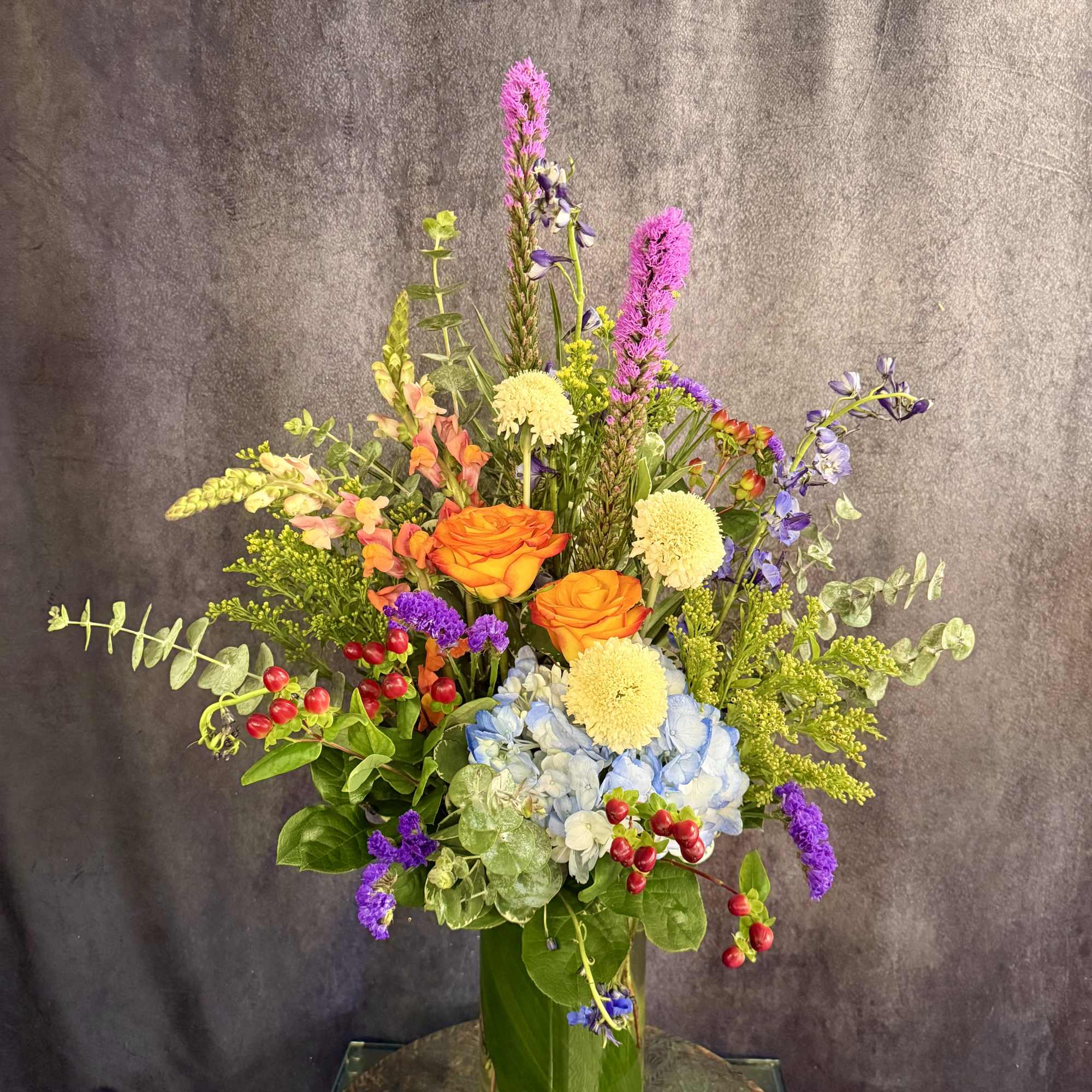 This stunning tall modern arrangement filled with vibrant colors such as red