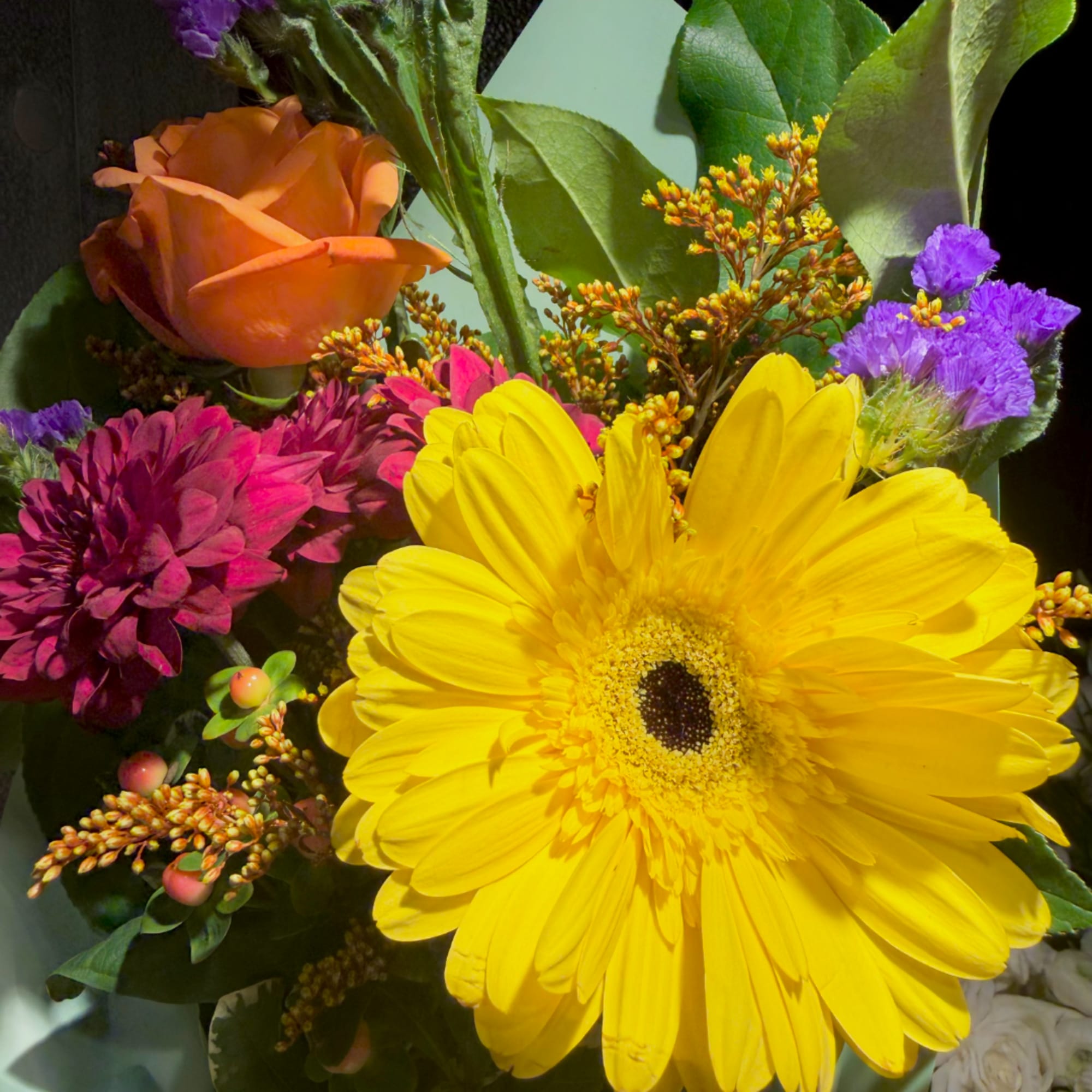 Mixed bouquet with a yellow gerbera daisy, orange rose, and purple flowers